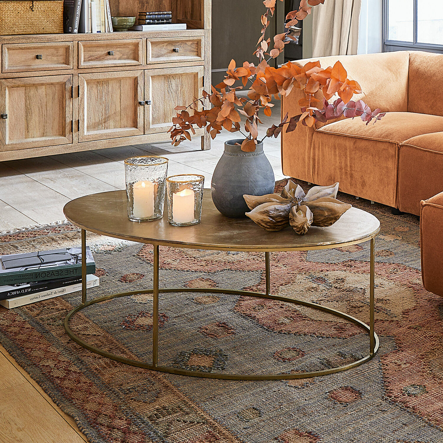 Couchtisch Leron Ovaler Couchtisch mit messingfarbenem Metallplatte auf Teppich vor orangefarbenem Sofa im Wohnzimmer