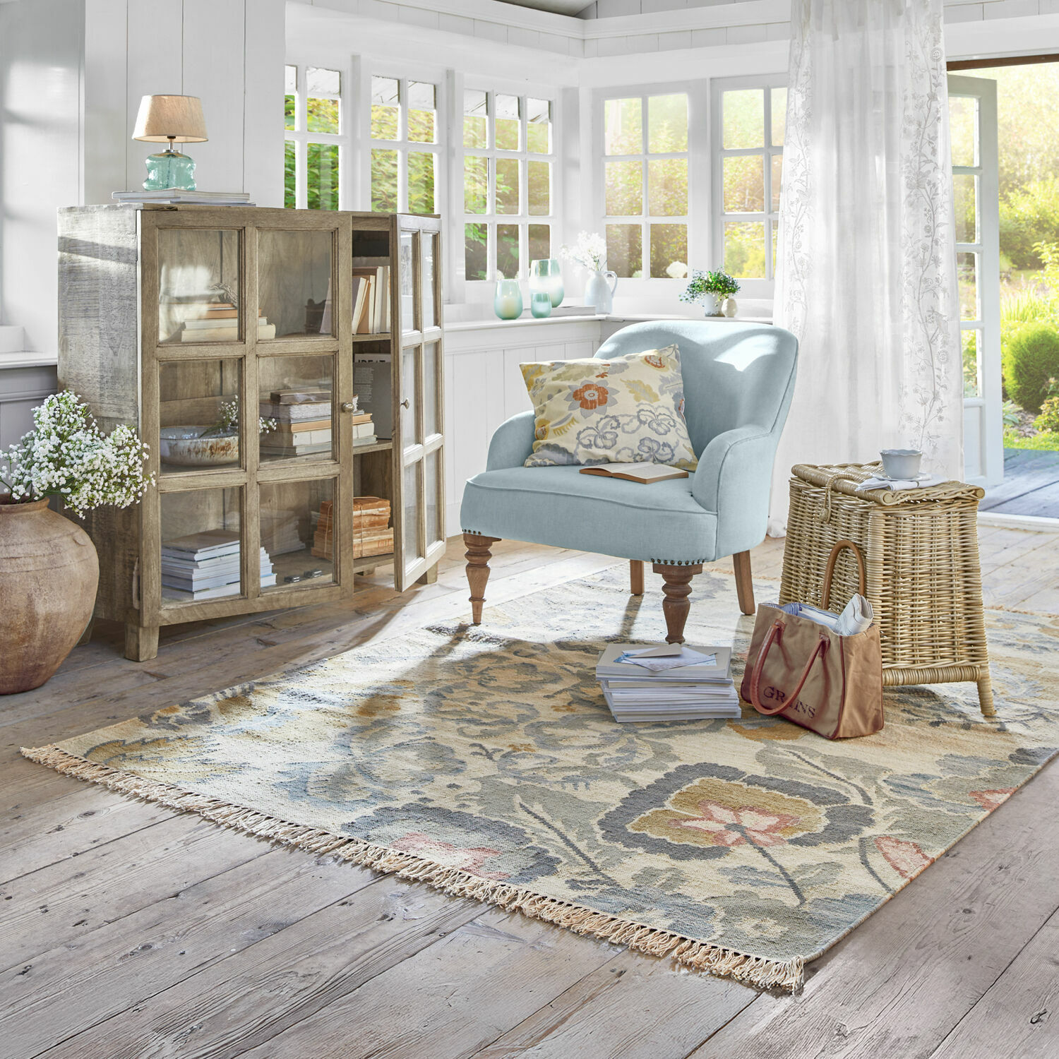 Teppich Sussex Gemütlicher hellblauer Sessel mit Holzbeinen auf gemustertem Teppich in hellem Wohnzimmer mit Tageslicht