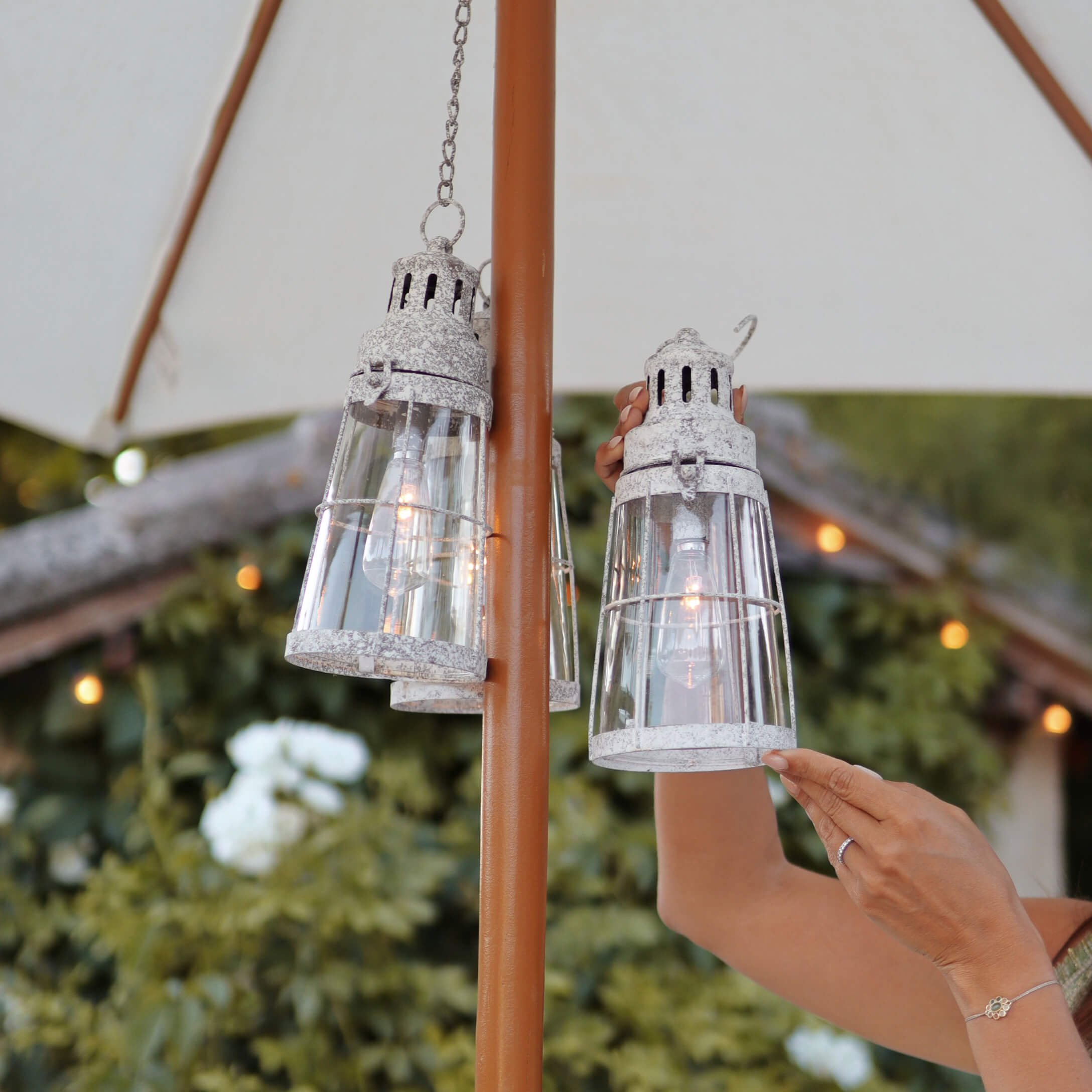 Glaslaterne mit weißem Vintage-Metall, hängend an Gartenschirm, dekorative Außenbeleuchtung