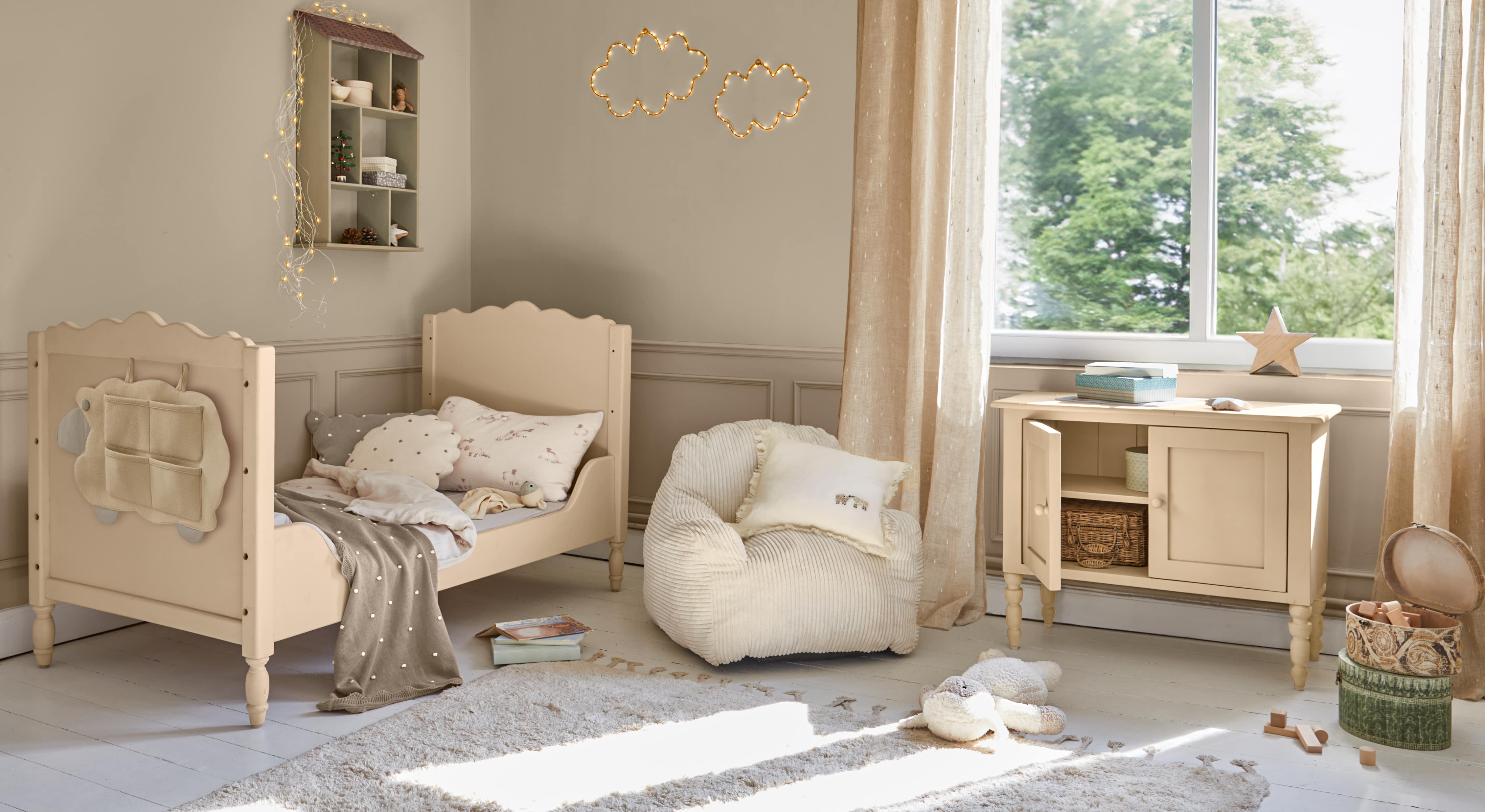 Beiges Kinderbett aus Holz mit weichen Kissen und passendem Schrank in hellem Kinderzimmer