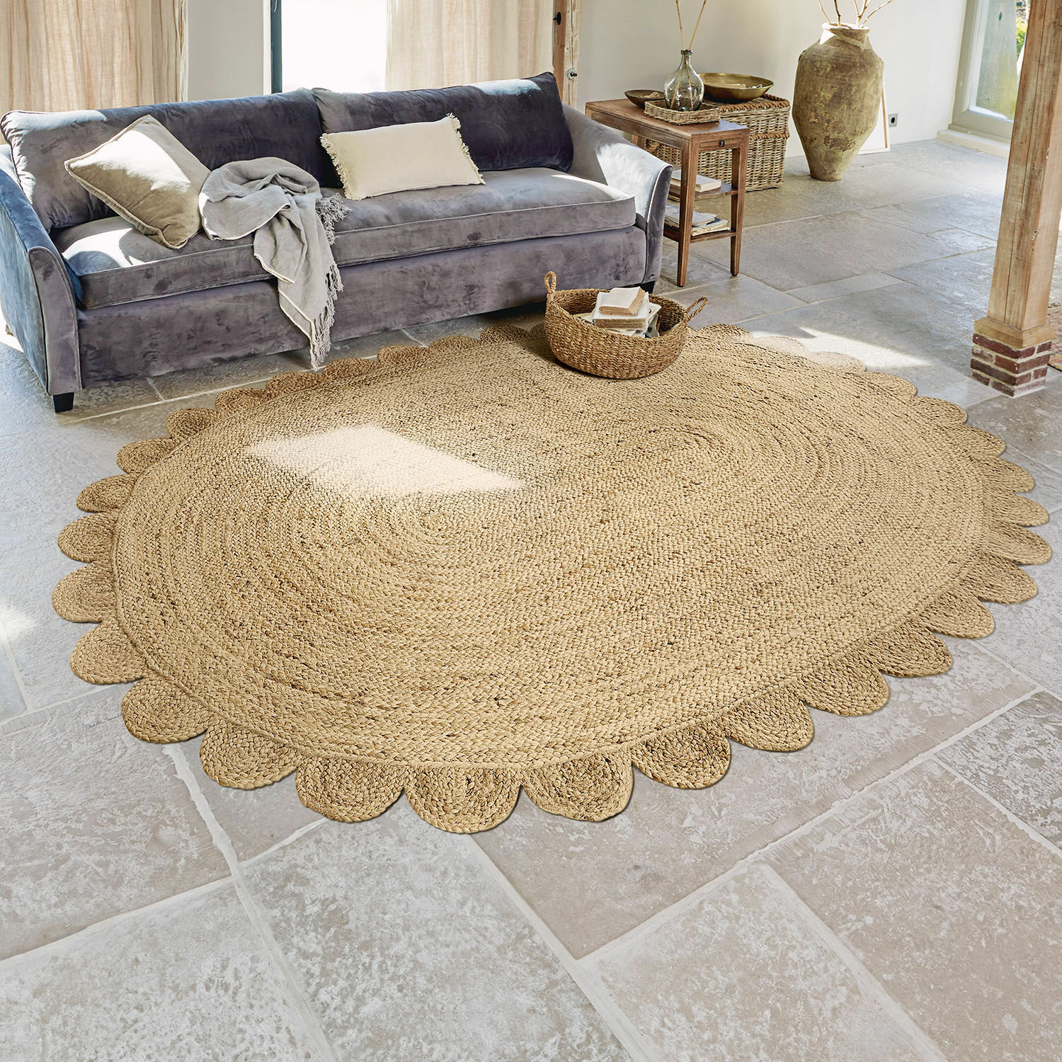 Teppich Ferce Runder Jute-Teppich in Naturfarbe mit dekorativem Rand im Wohnzimmer mit grauem Sofa