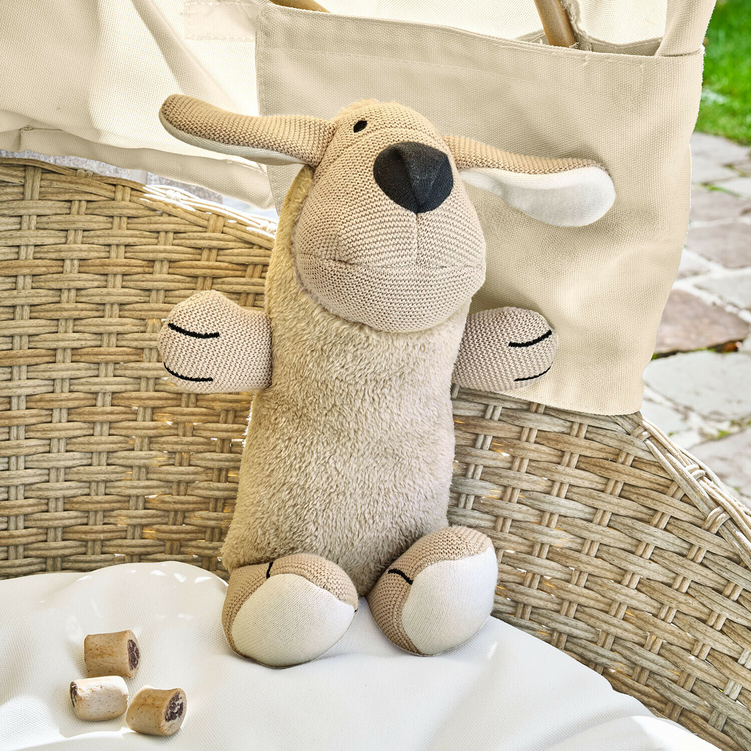 Hundespielzeug Wuffie Beige Kuscheltier Schaf mit weichem Plüschkörper und gestrickten Details auf Rattanstuhl