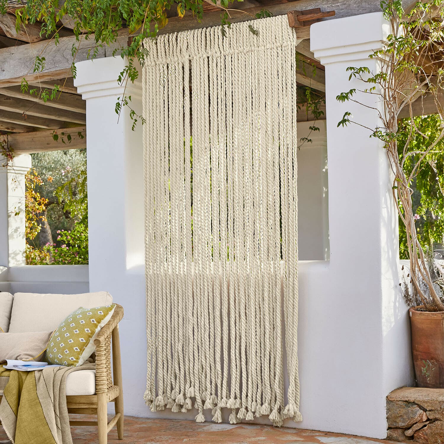 Dekorativer Vorhang aus dicken weißen Baumwollseilen im Boho-Stil auf Terrasse