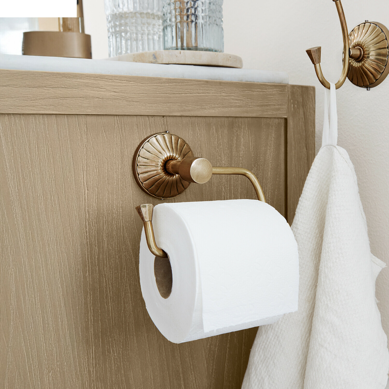 Toilettenpapierhalter Terling Messing-Toilettenpapierhalter mit Haken und weißem Handtuch an hellem Holzschrank