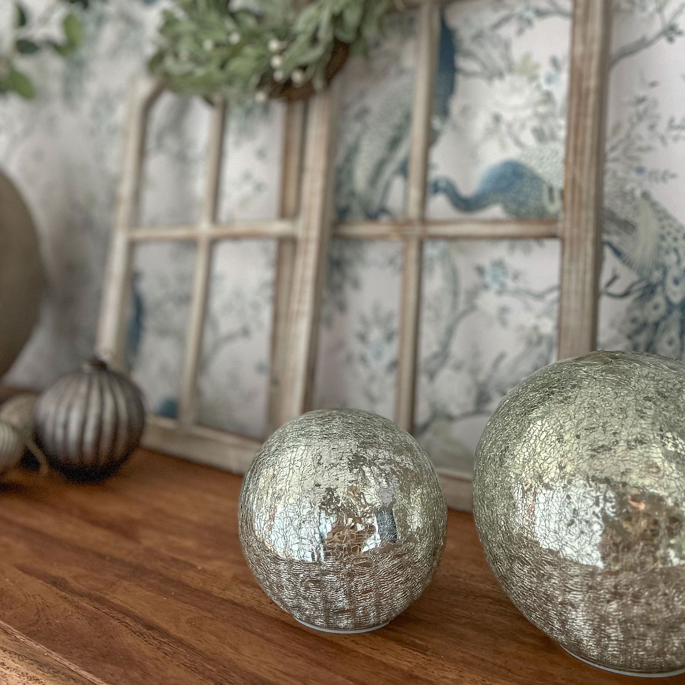Dekorative silberne Kugeln mit rissiger Oberfläche auf Holztisch für Wohnraumdeko