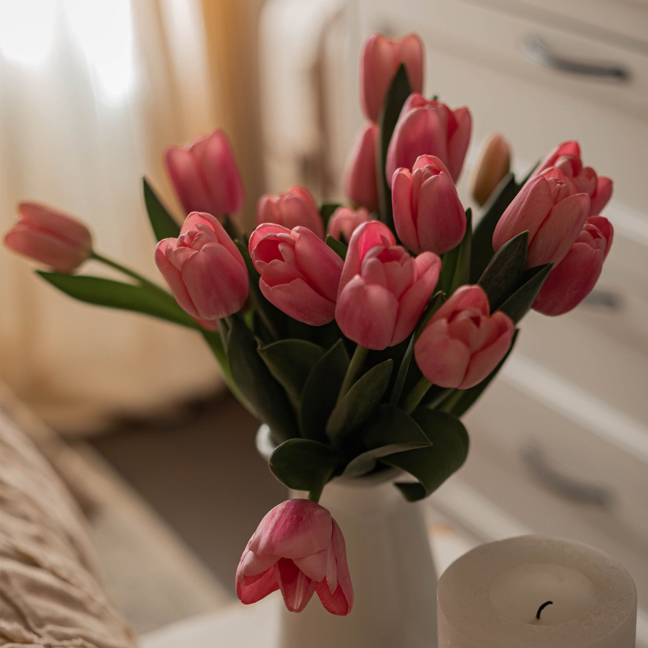 Strauß rosa Tulpen in weißem Vase vor hellem Schlafzimmerhintergrund