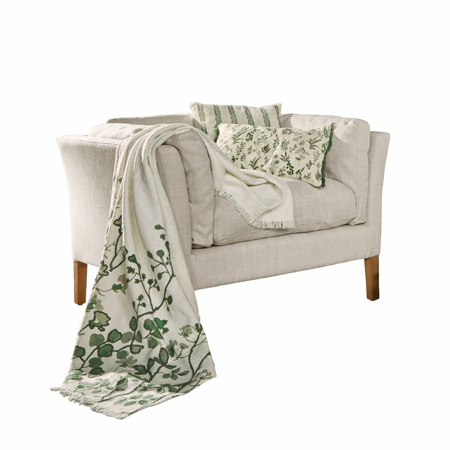 Sessel Lourvière Beiges Sofa aus Stoff mit grünen Kissen und dekorativer Decke mit Pflanzenmuster