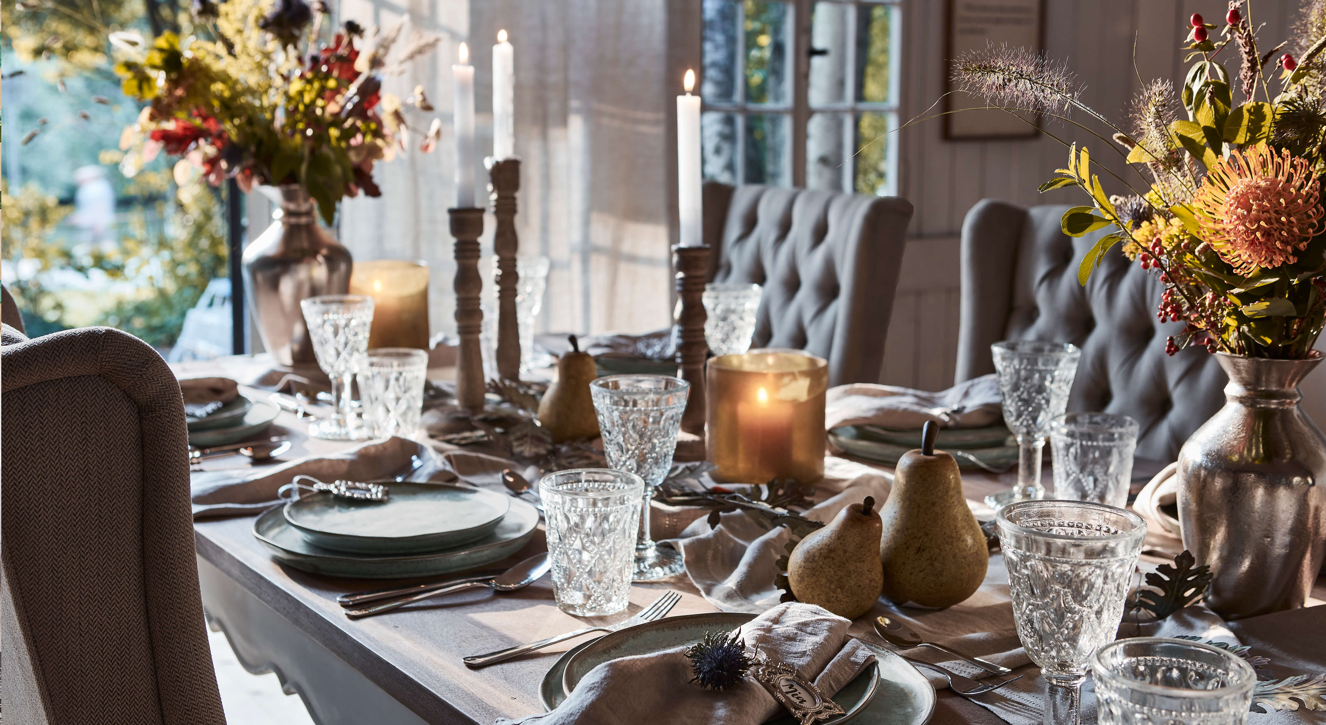 Eleganter gedeckter Tisch mit grauen Tellern, Kristallgläsern und Kerzen in gemütlichem Ambiente