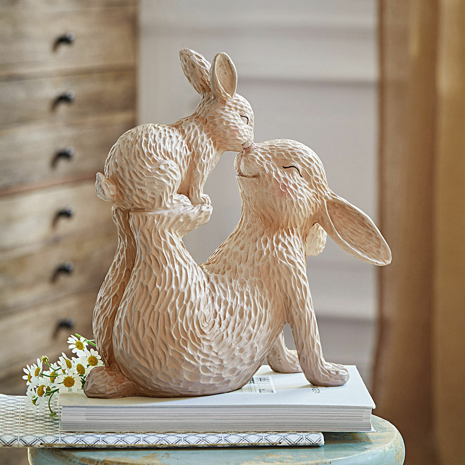 Deko-Hase Trista Beige Keramikfigur von zwei Kaninchen in spielerischer Pose auf einem Tisch mit Büchern