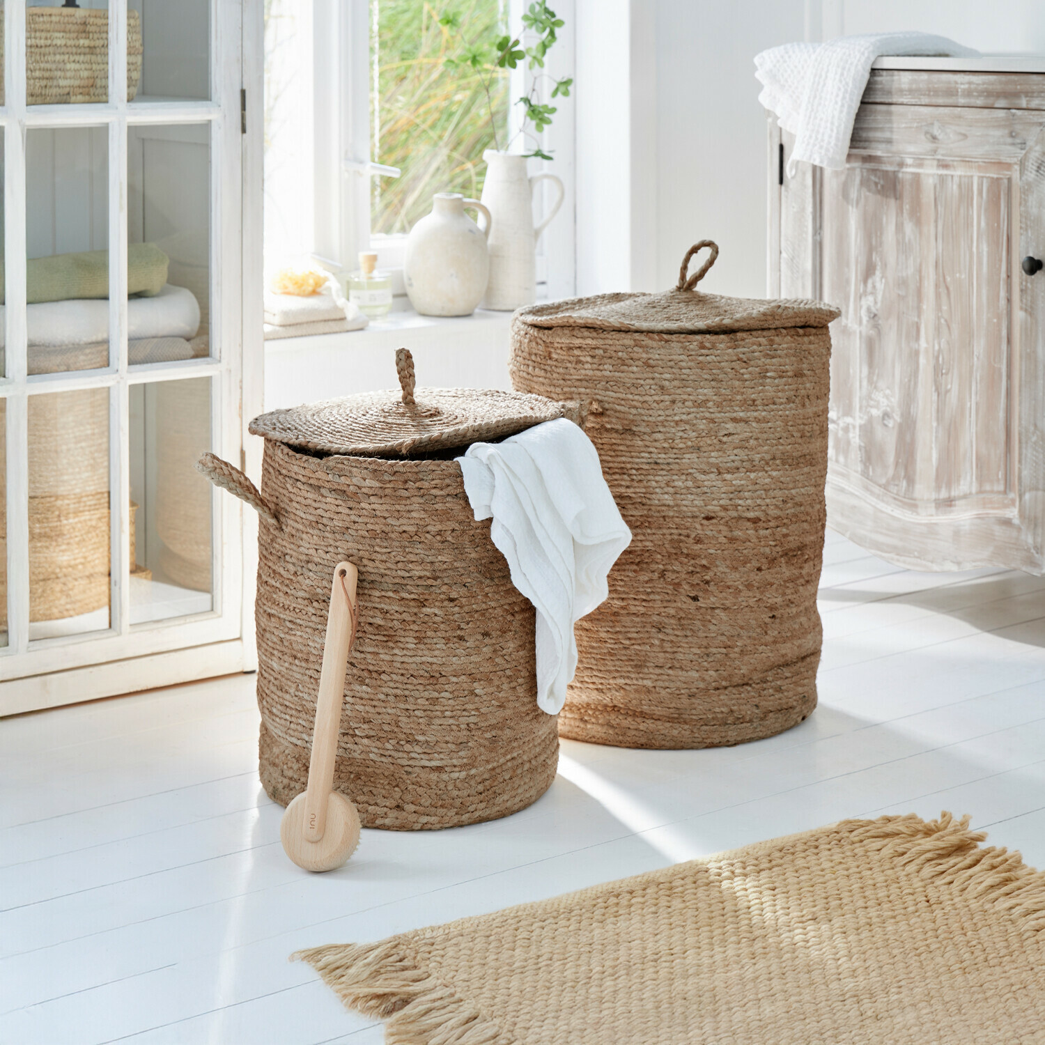 Zwei runde Wäschekörbe aus natürlicher Jute in Beige in einem hellen Badezimmer