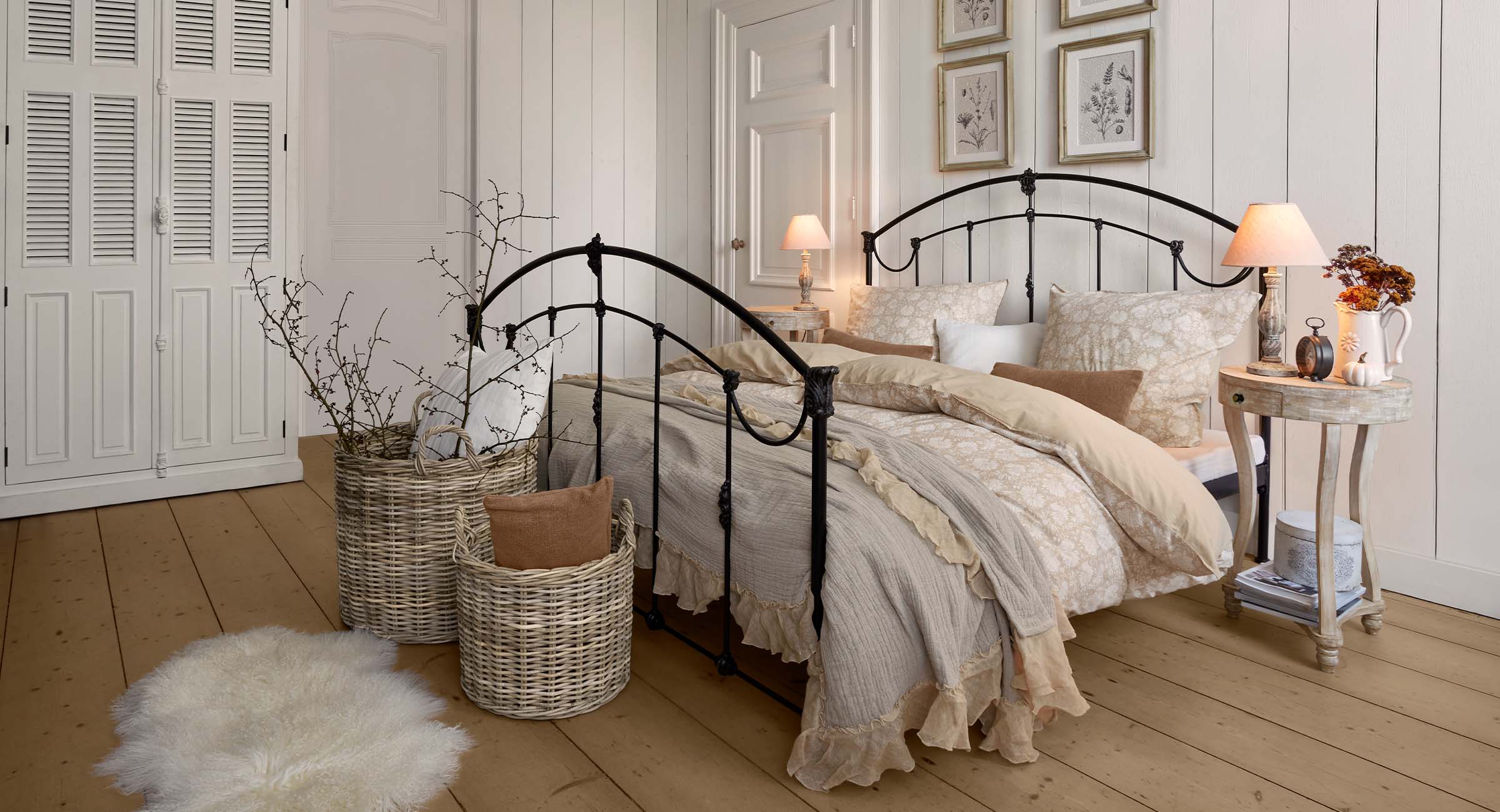 Gemütliches Schlafzimmer mit schwarzem Metallbett und cremefarbener Bettwäsche mit Blumenmuster
