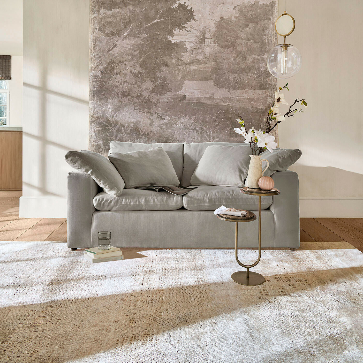 Sofa Everholt Graues Sofa mit weichen Kissen in hellem Wohnzimmer mit dekorativem Beistelltisch und Teppich