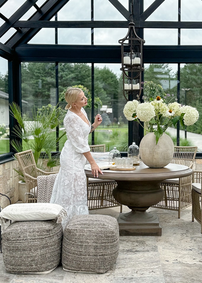 Gemütlicher Wintergarten mit runden Steintisch, Korbstühlen und weißer Blumendekoration
