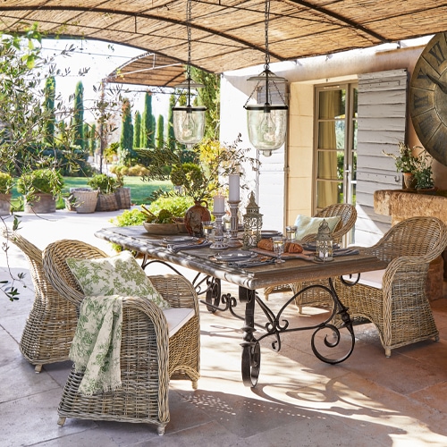 Gartenmöbel-Set aus Rattan und Metall in Naturtönen auf Terrasse mit Dekorationen und Lampen