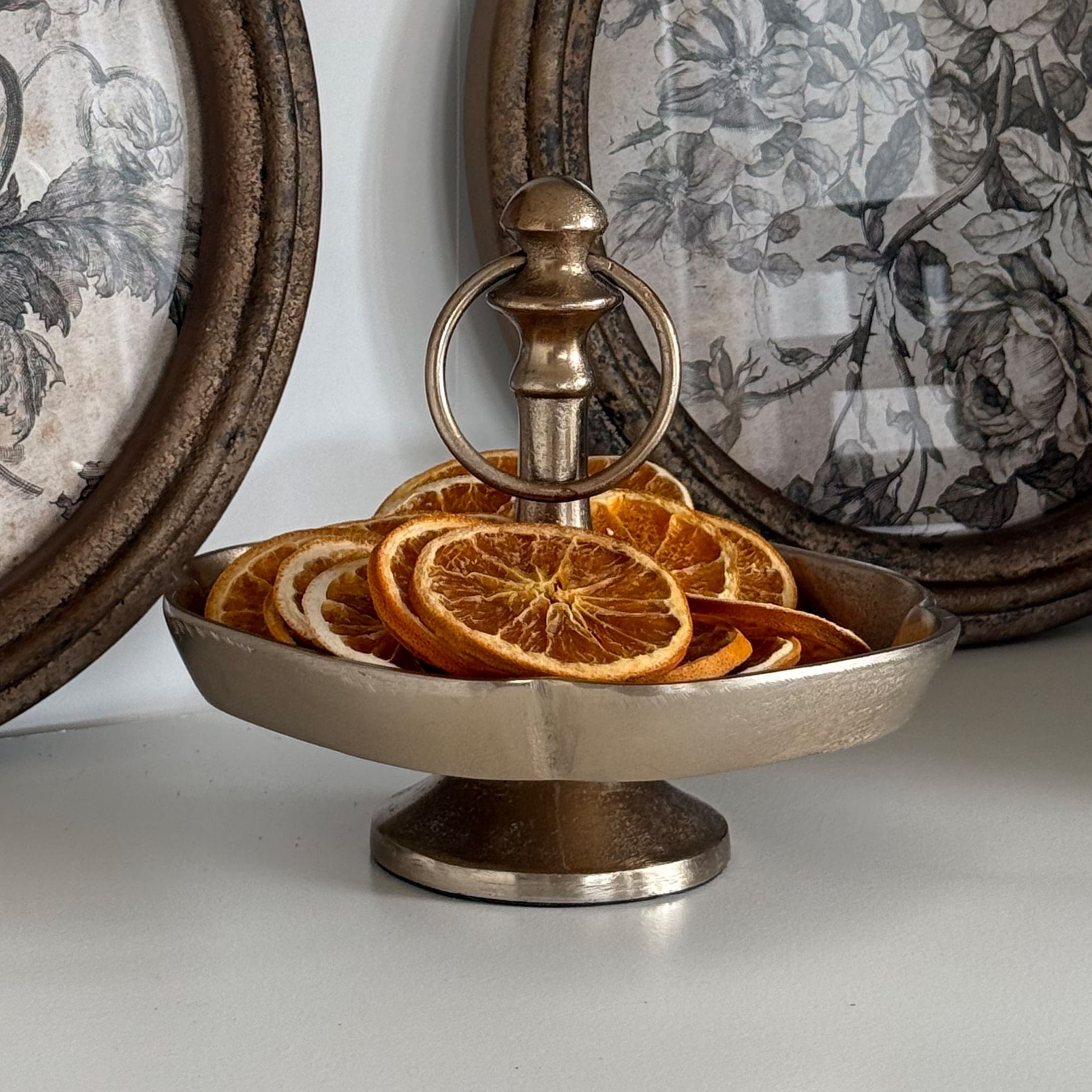 Silberne Metall-Etagere mit Griff und getrockneten Orangenscheiben als herbstliche Dekoration