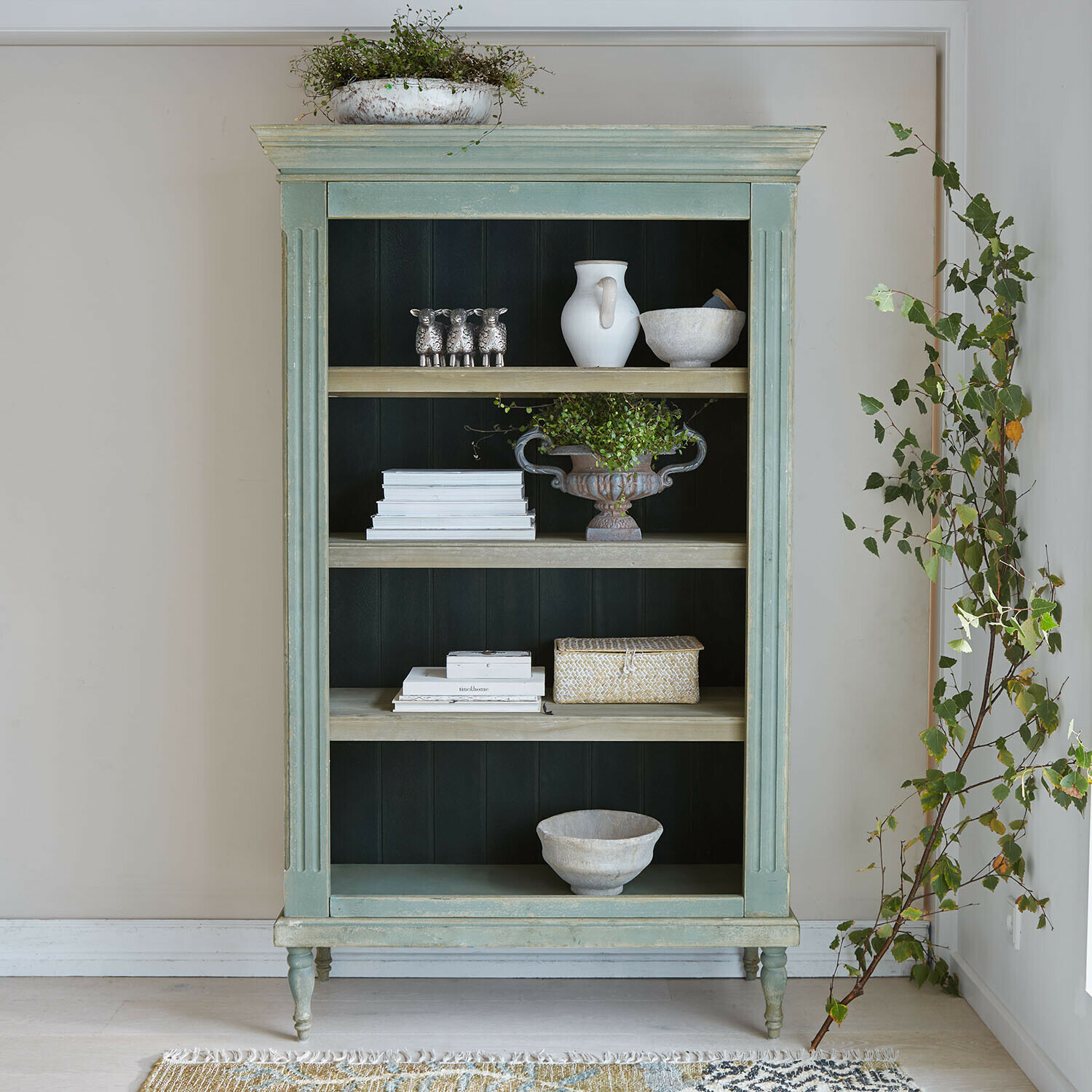 Grüner Holzschrank mit Regalen, dekoriert mit Pflanzen und weißen Gefäßen, Vintage-Stil