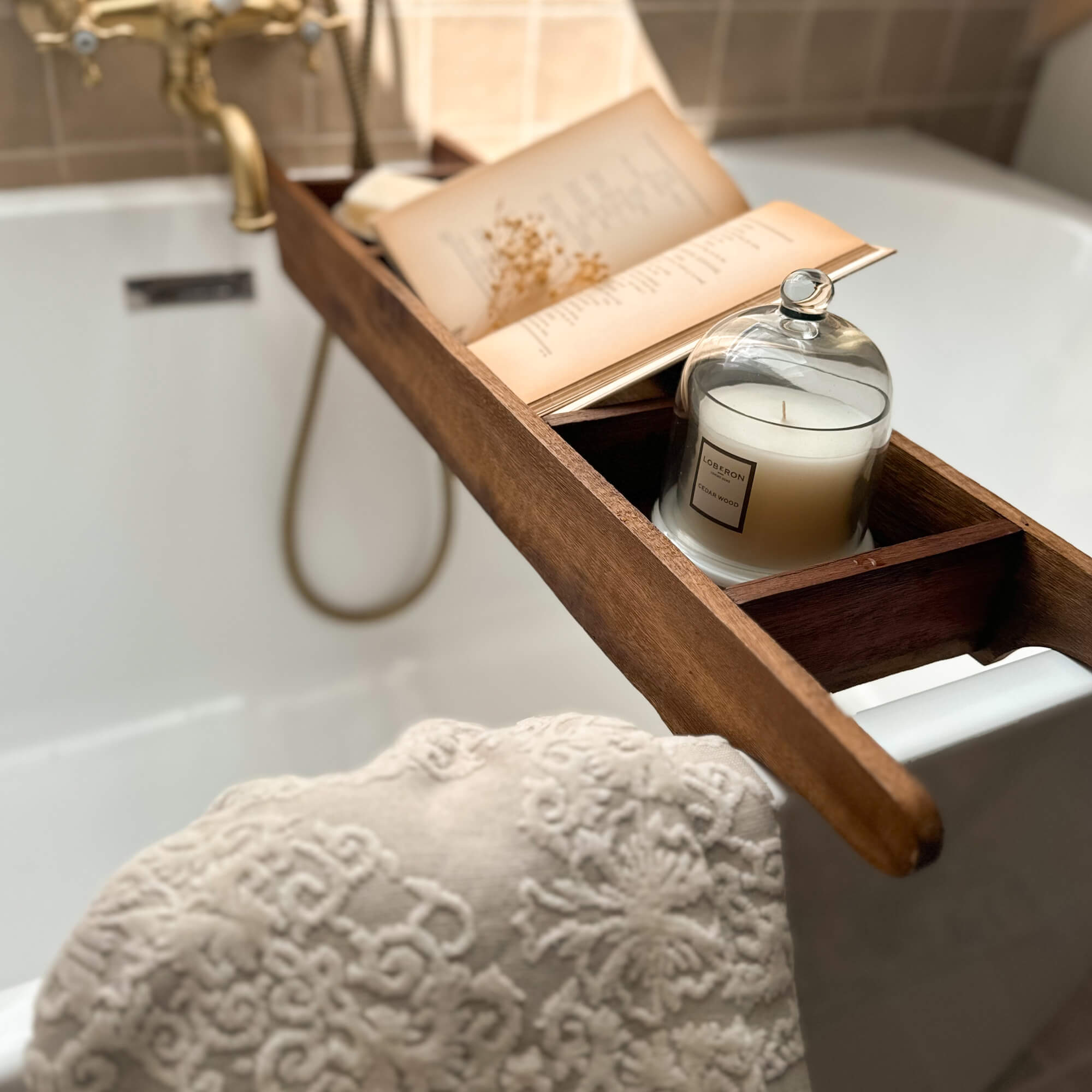 Holzbadewannenablage mit weißer Kerze und offenem Buch, entspannendes Badezimmerzubehör