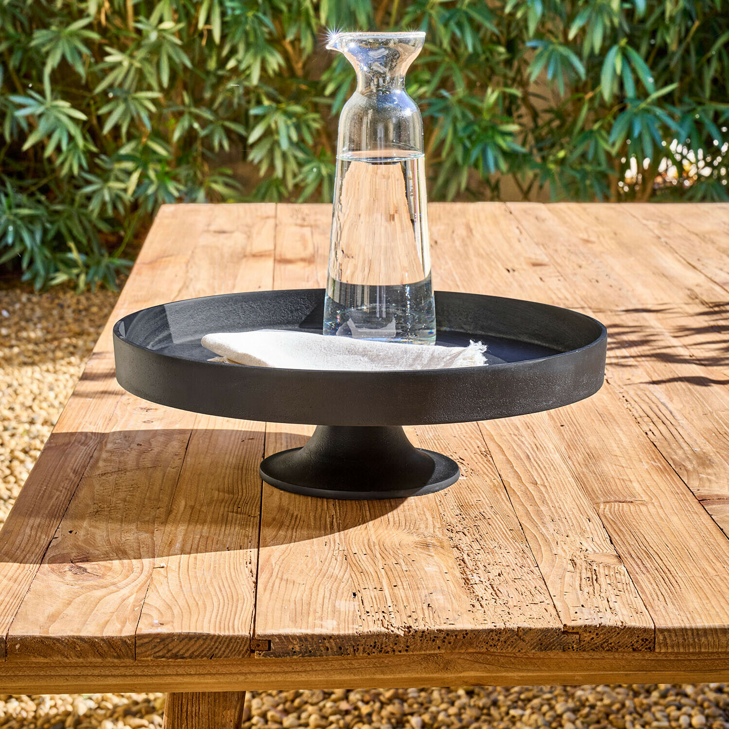 Etagere Varelle Schwarze Metall-Etagere auf Fuß mit klarem Glas-Krug und weißer Serviette auf Holztisch