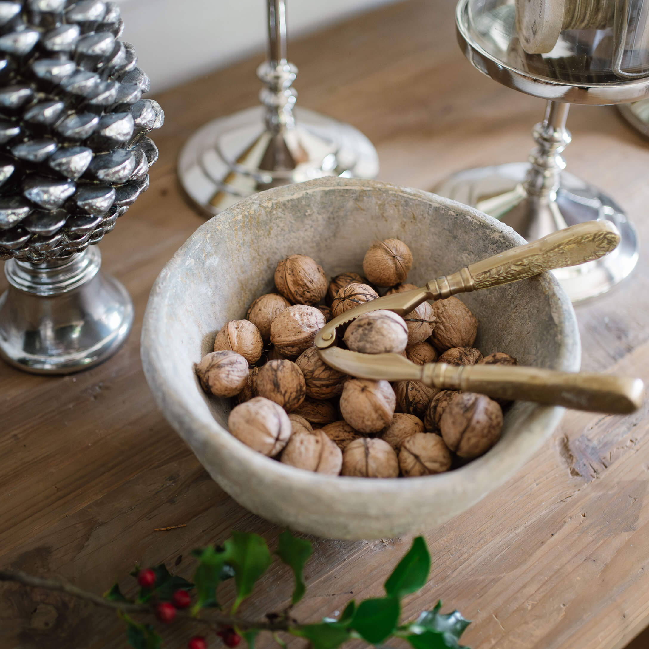 Steinschale mit Walnüssen und goldenem Nussknacker auf rustikalem Holztisch