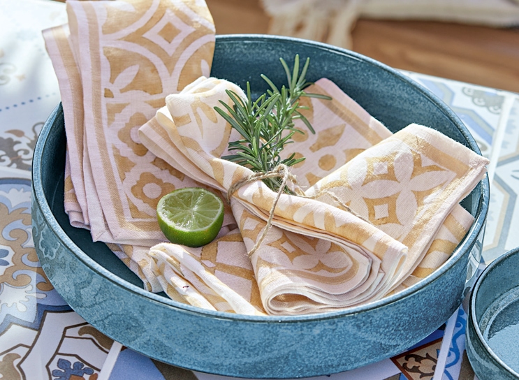 Blaue Keramikschale mit beige-weißen Leinenservietten und Limettenscheibe im mediterranen Stil