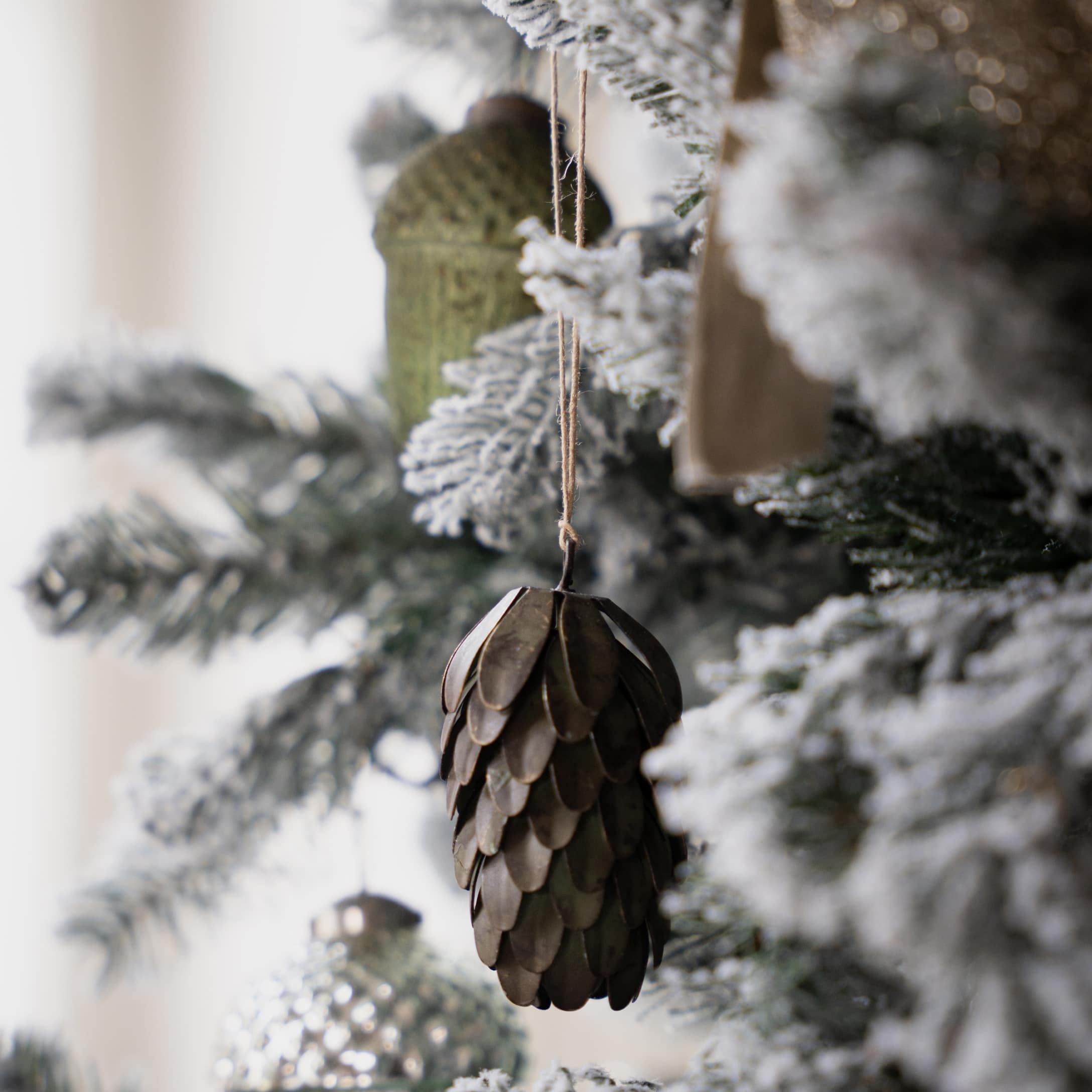 Braune Metall-Weihnachtsschmuckszapfen an schneebedecktem Weihnachtsbaum