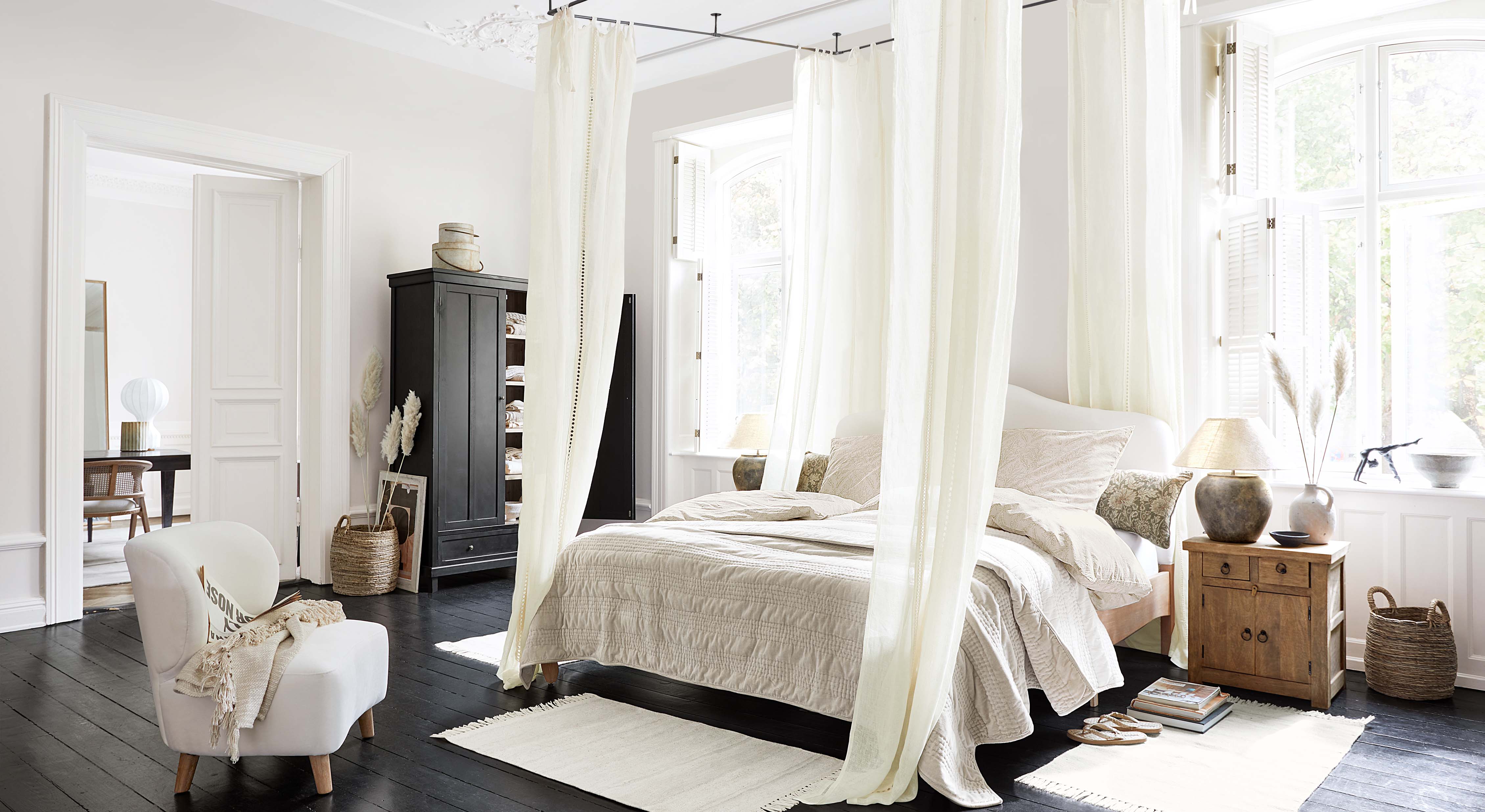 Gemütliches Schlafzimmer mit Himmelbett, hellbeiger Bettwäsche und skandinavischen Holzmöbeln