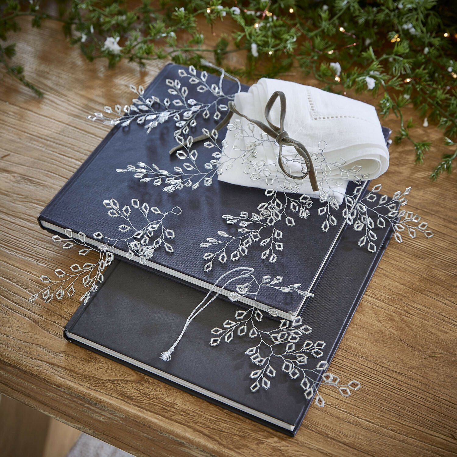Ornament 6er Set Alruna Zwei dunkelblaue und schwarze Alben auf Holztisch mit weißer Leinenserviette und Kristalldekoration