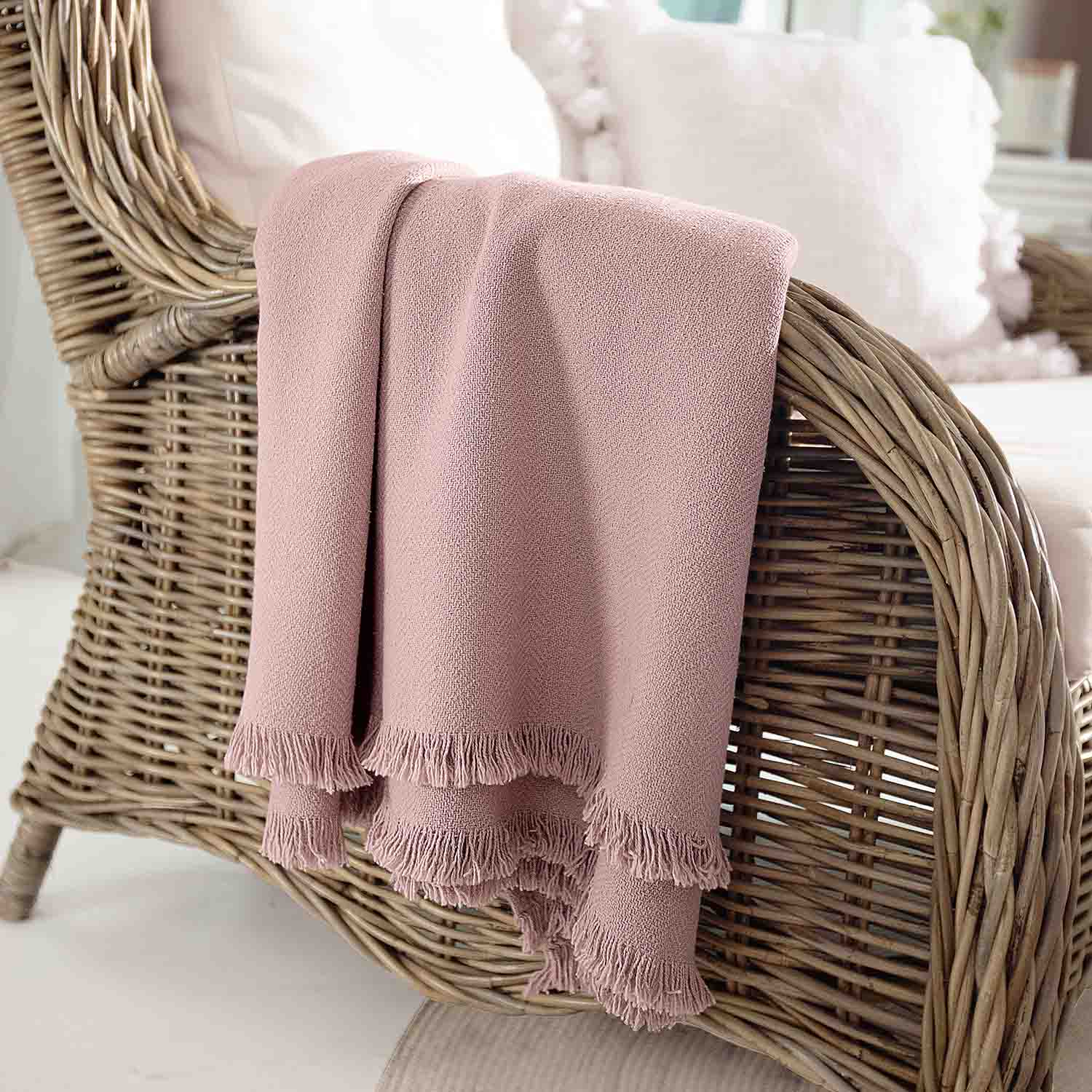 Rosa Decke aus weichem Material mit Fransen auf Rattansessel, gemütliche Wohnraumdekoration