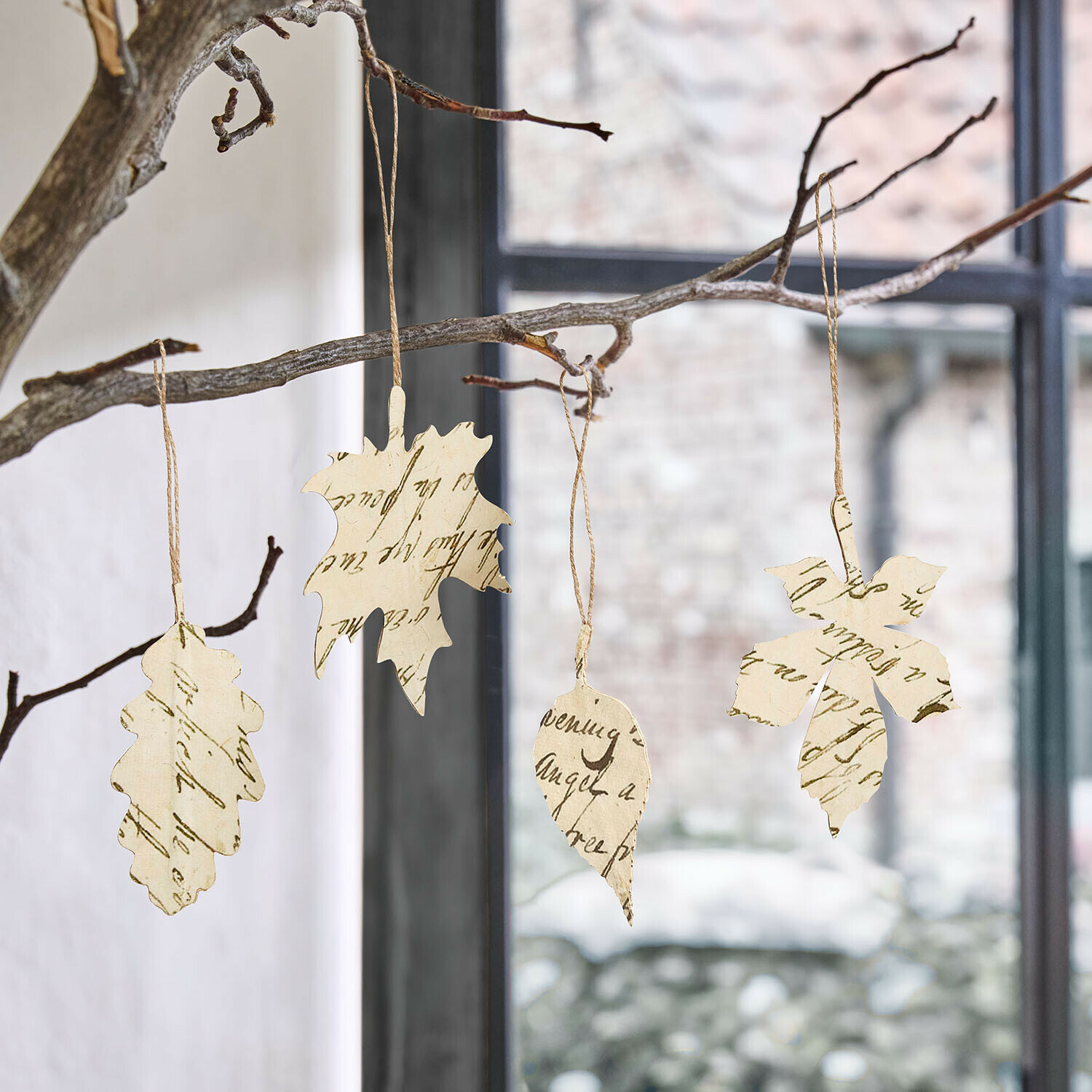 Papierblätter mit Schrift als Dekoration an Zweigen hängend vor Fenster