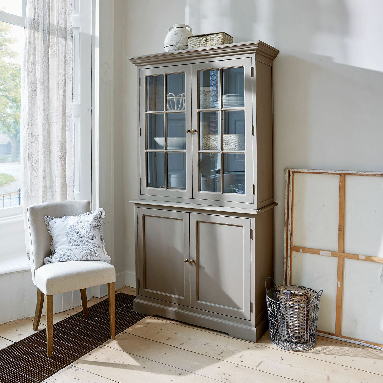 Schrank Rosebrook Grauer Holzvitrinenschrank mit Glastüren und Regalen in hellem Wohnzimmer