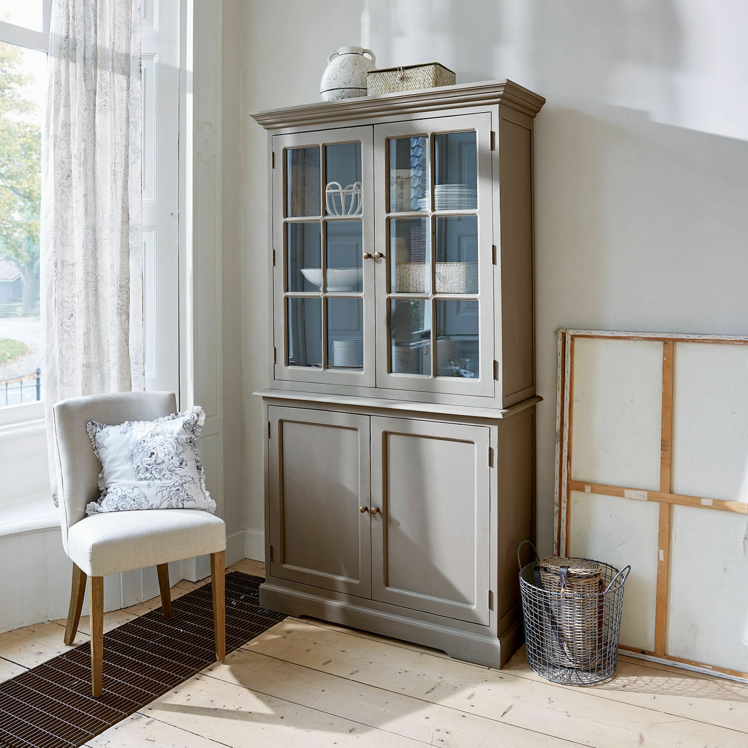 Schrank Rosebrook Grauer Holzvitrinenschrank mit Glastüren und Regalen in hellem Wohnzimmer