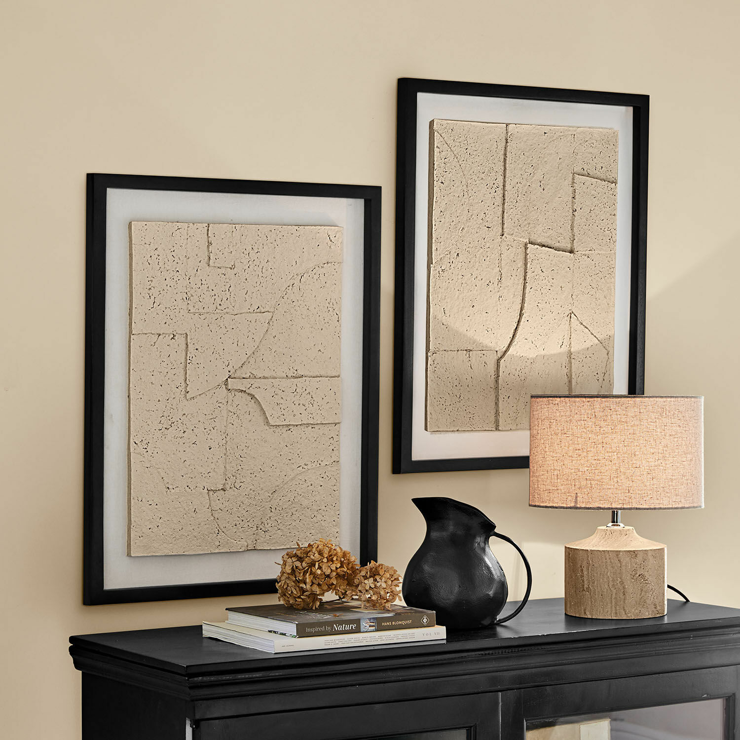 Bild 2er Set Lavinois Zwei beige Reliefbilder in schwarzen Rahmen über schwarzem Sideboard mit Lampe und schwarzem Krug