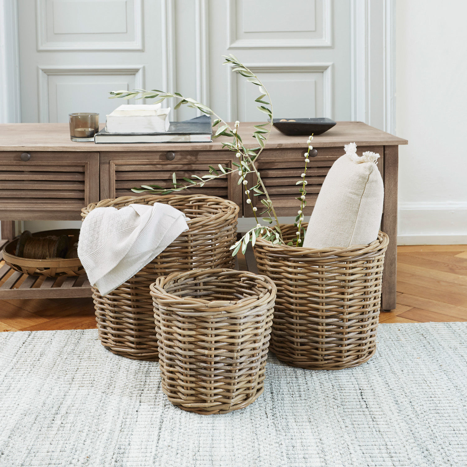 Korb 3er Set Avar Drei natürliche Korbsets aus Rattan zum Aufbewahren im Wohnbereich auf hellem Teppich.