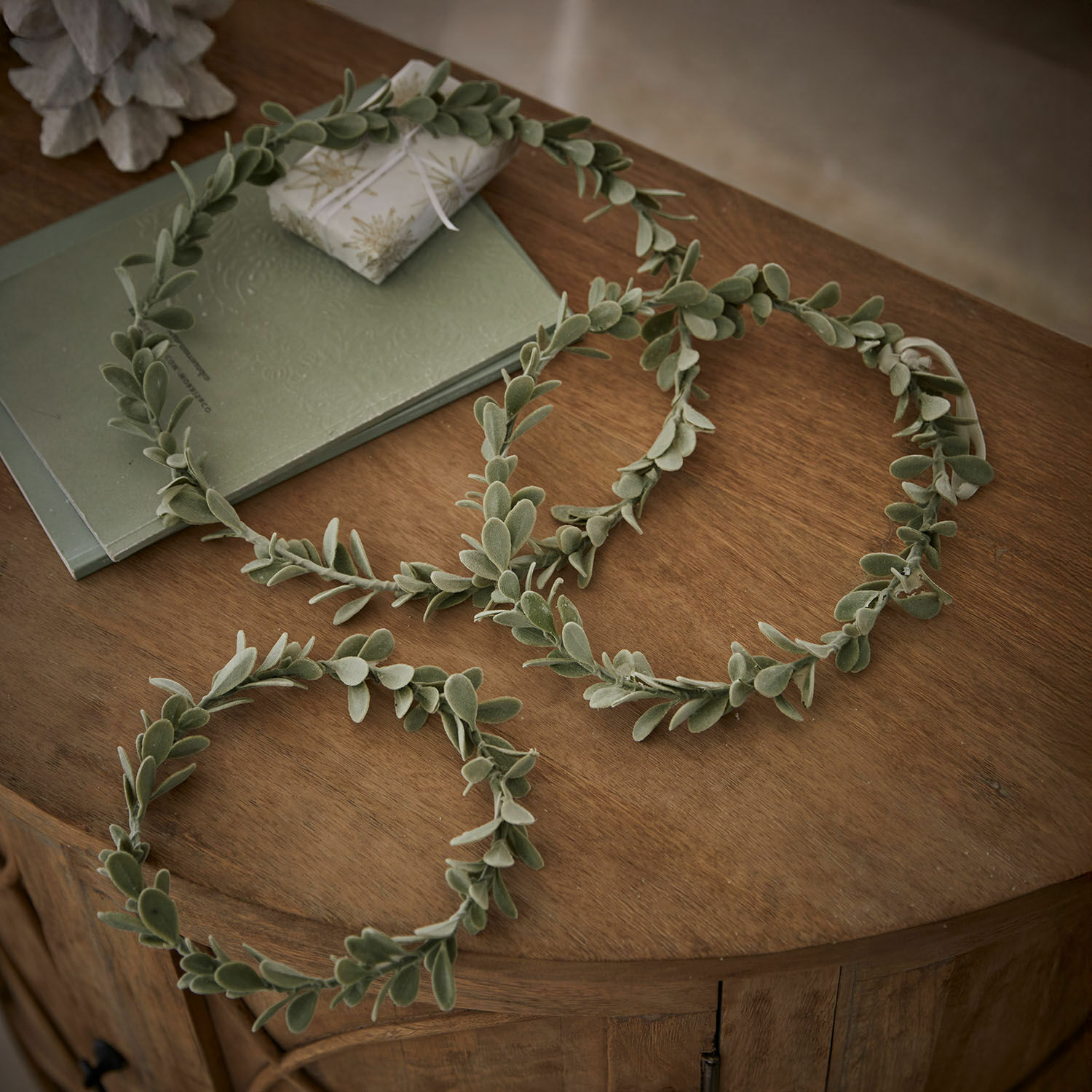 Dekorative grüne Kränze aus weichen Blättern auf Holztisch, natürliche Wohnraumdekoration