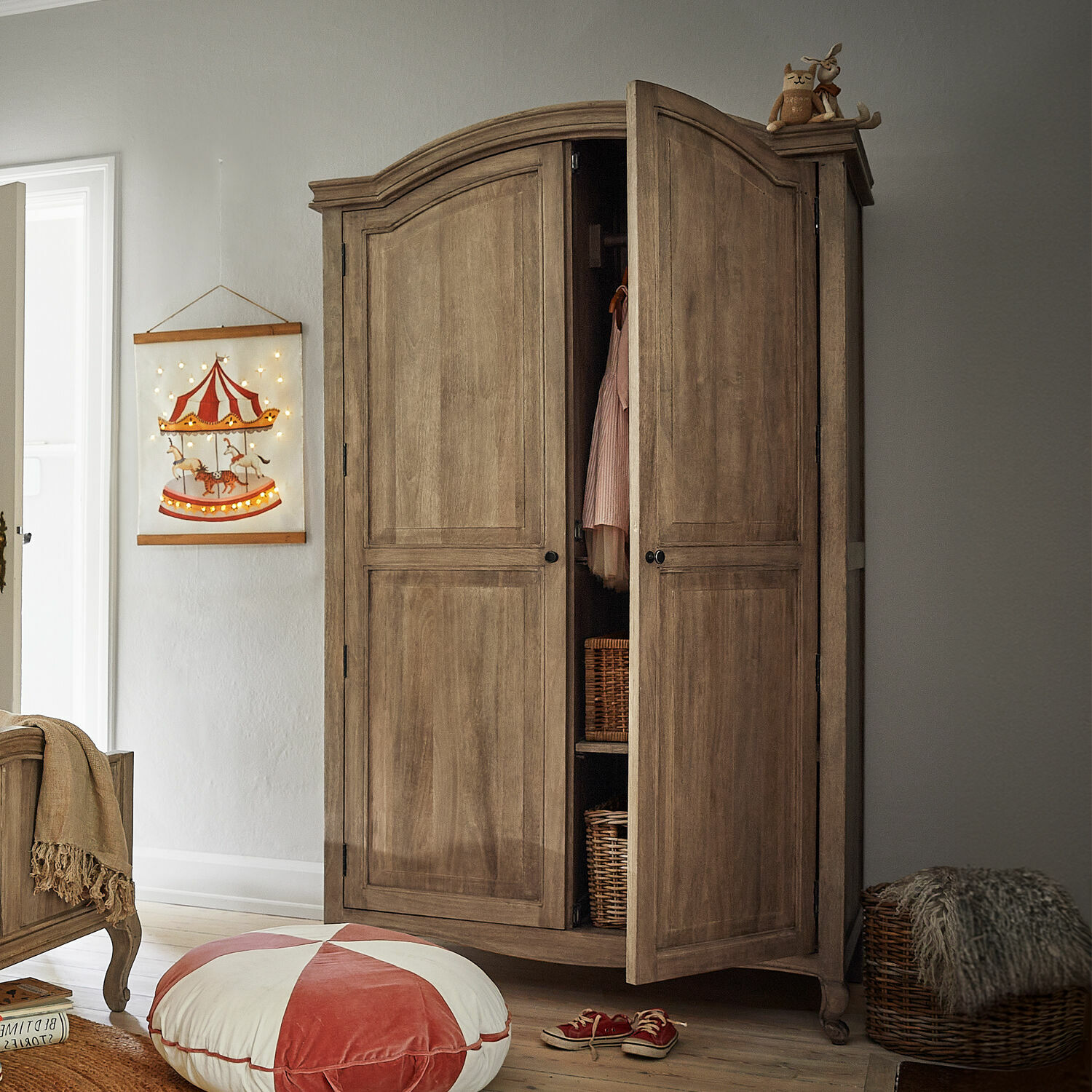 Kleiderschrank Éveilou Holzschrank in Naturfarbe mit offenen Türen, Weidenkörben und Dekorationen in einem Kinderzimmer