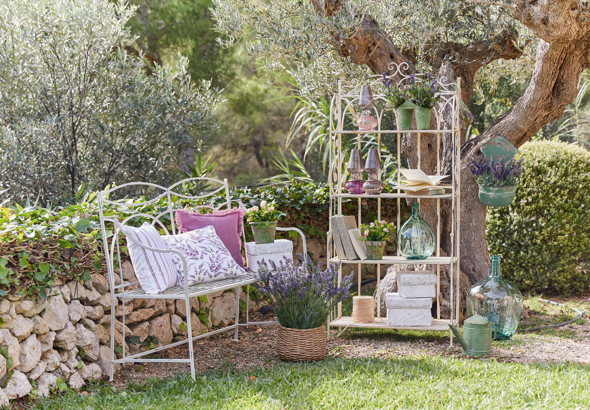 Weißes Metallregal und Gartenbank mit Lavendel und Dekorationen im Garten, rustikales Gartenmöbel