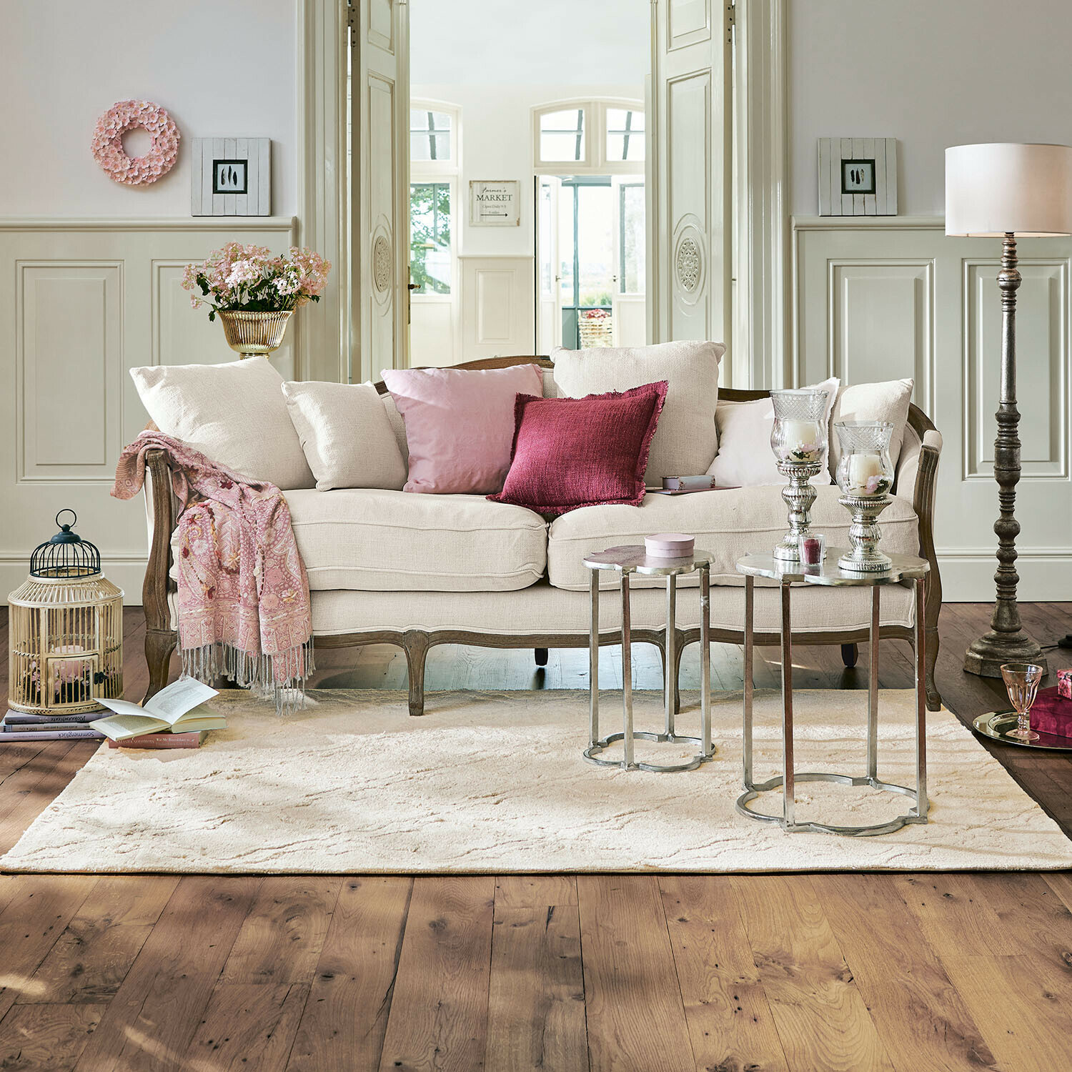 Sofa Monneville Beiges Sofa mit Holzrahmen und rosa Kissen in elegantem Wohnzimmer mit Teppich und Beistelltischen