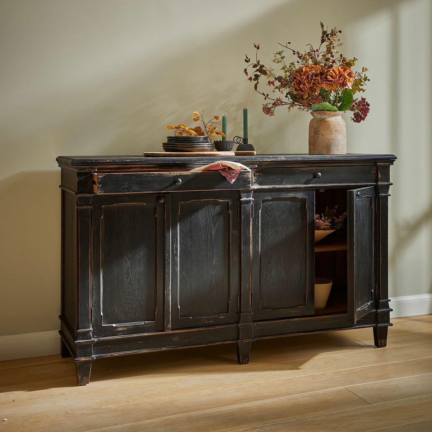 Sideboard Chaveline Schwarze Holzkommode mit antikem Finish und dekorativen Türen auf hellem Holzboden.