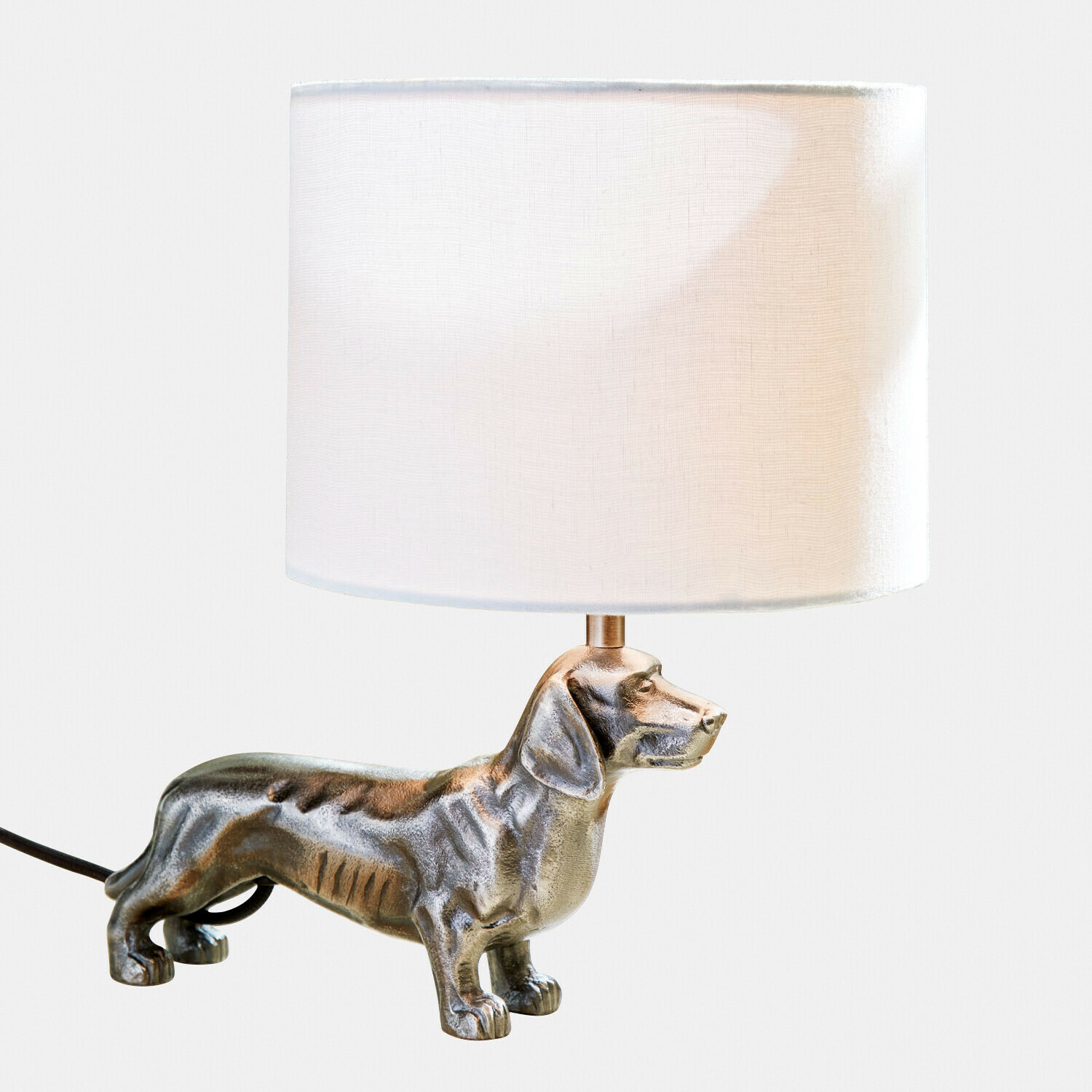 Tischlampe mit weißem Lampenschirm und silberner Dackelfigur als Lampenfuß