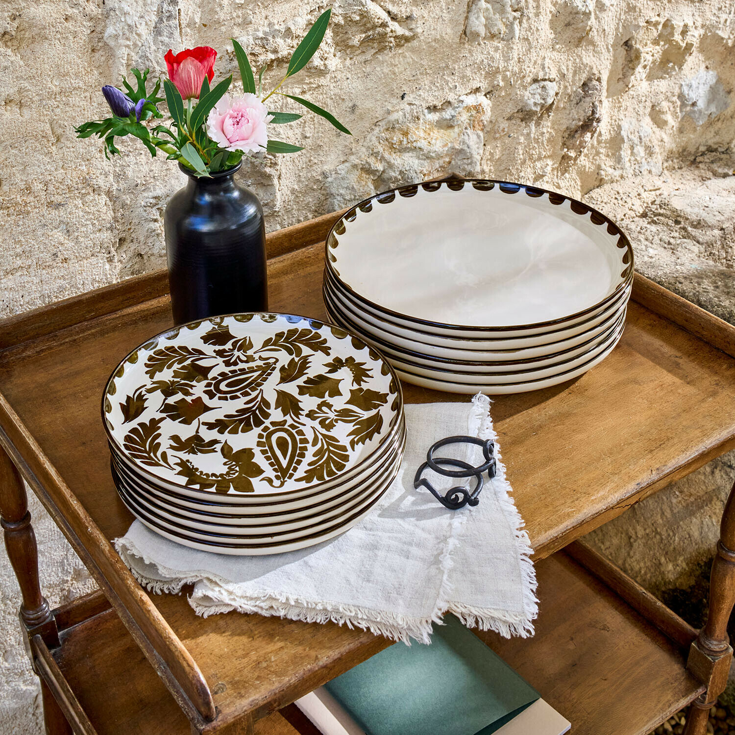 Teller 12er Set Tazira Set aus cremefarbenen Keramiktellern mit braunem Muster auf Holztisch mit schwarzer Vase und Blumen