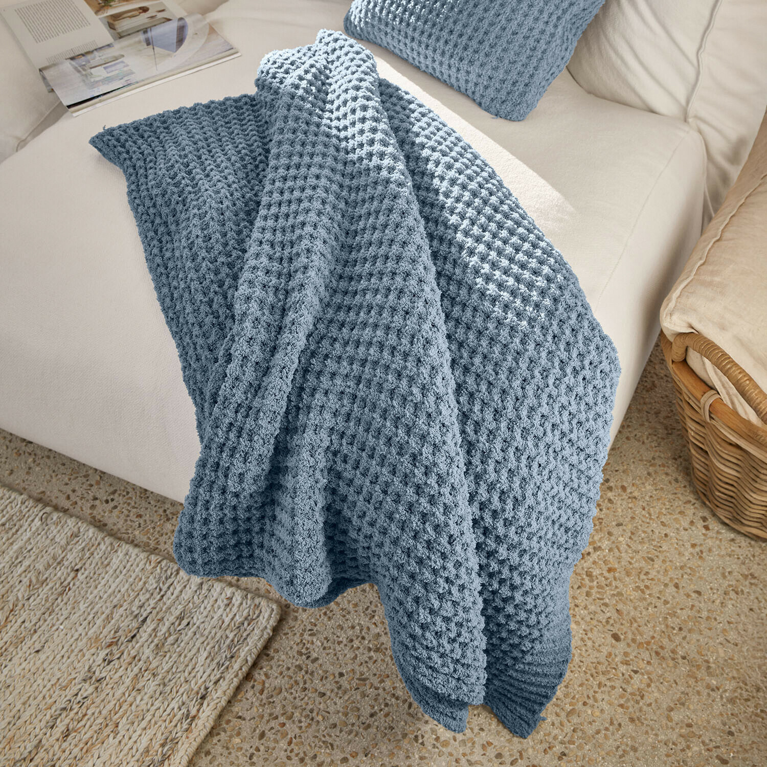 Plaid Ysilda Weiche blaue Waffeldecke auf hellem Sofa, dekorativer und gemütlicher Wohnzimmerschal