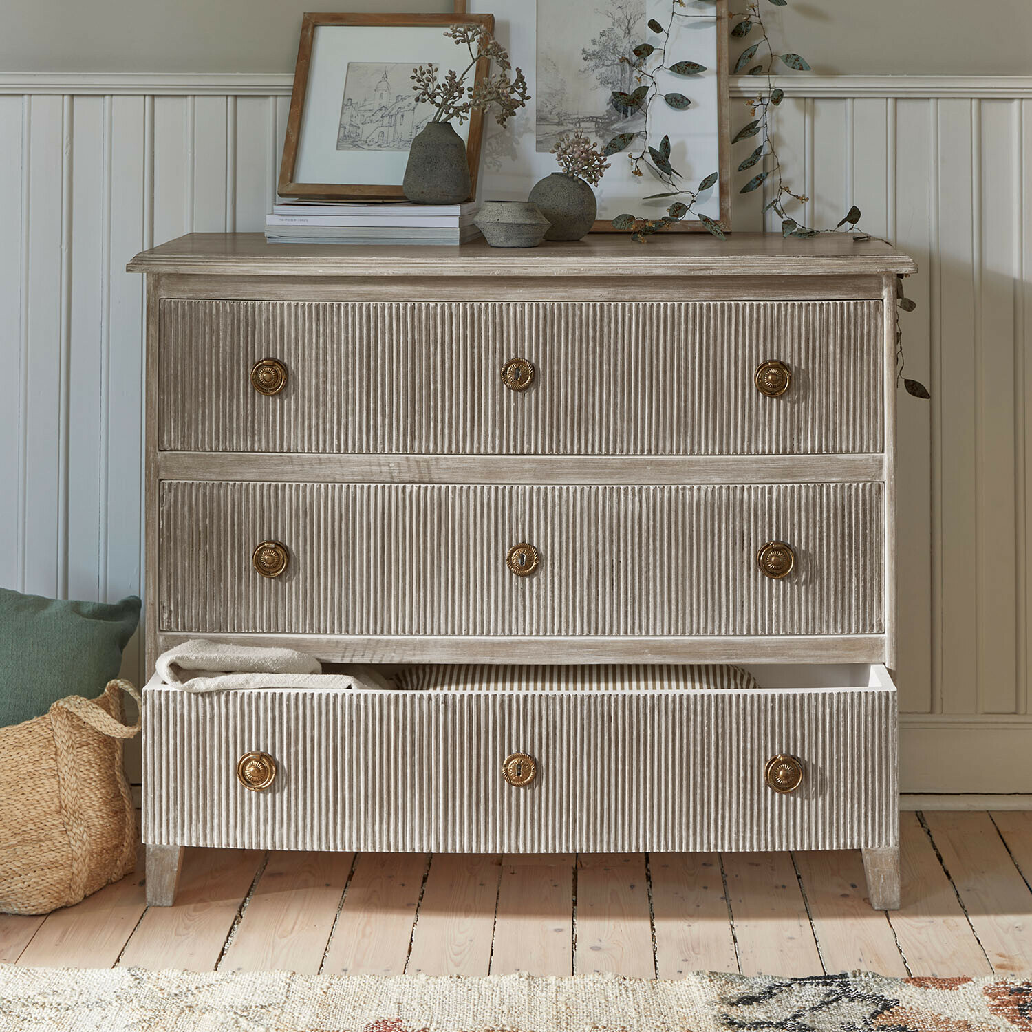 Kommode aus geriffeltem Holz in Beige mit Messinggriffen und Dekorationen auf der Ablage