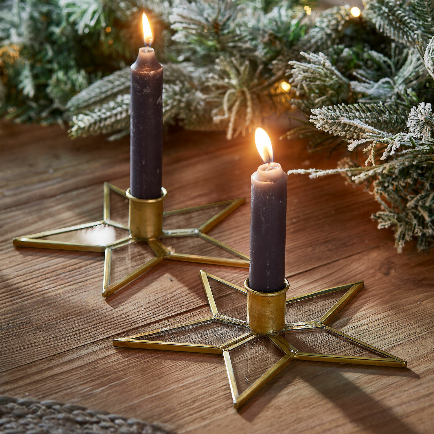 Kerzenständer 2er Set Zaydan Zwei sternförmige Kerzenhalter aus Glas und goldenem Metall mit violetten Kerzen auf Holztisch