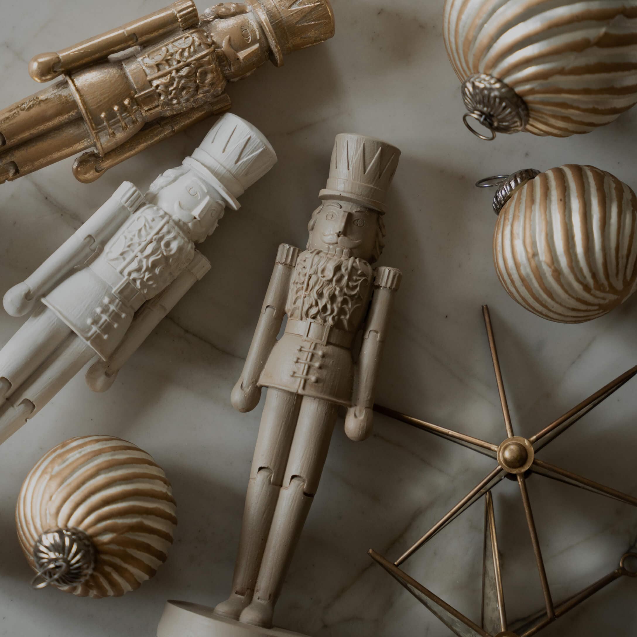 Holz-Nussknackerfiguren und goldene Weihnachtskugeln auf Marmorhintergrund, festliche Dekoration