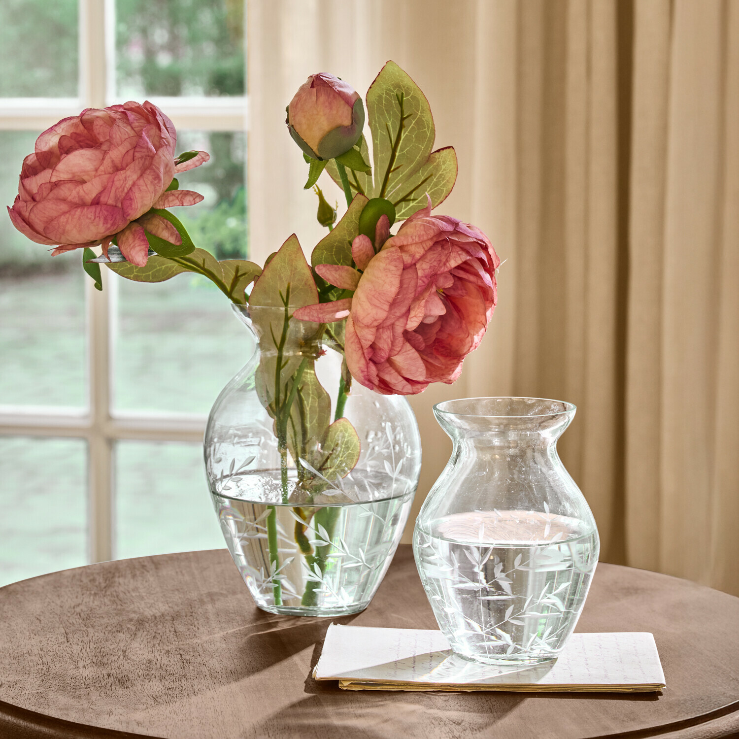 Vase 2er Set Paimpont Transparente Glasvasen mit graviertem Blattmuster, eine mit rosa Blumen, auf einem Holztisch