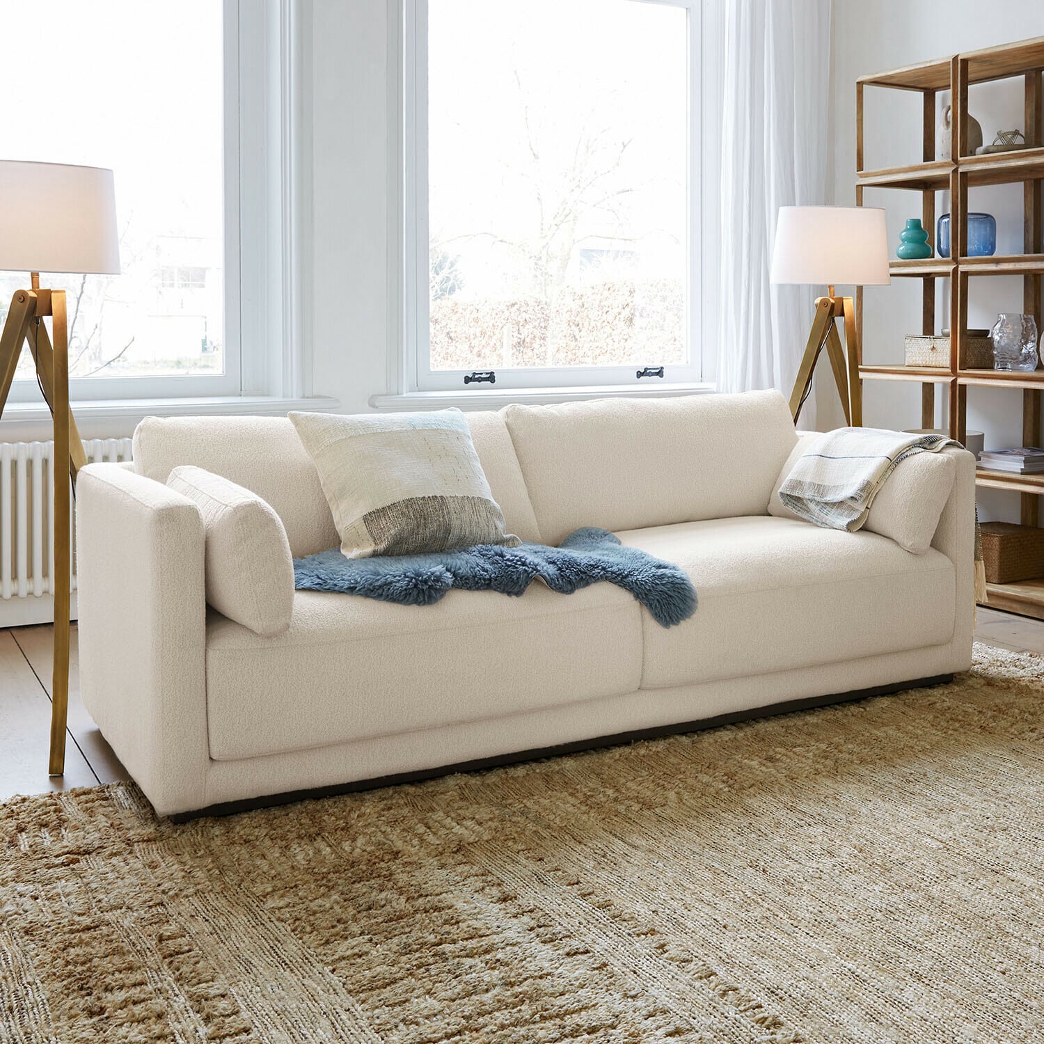 Sofa Thamira Moderne cremefarbene Sofa mit weichem Stoff und dekorativen Kissen im hellen Wohnzimmer