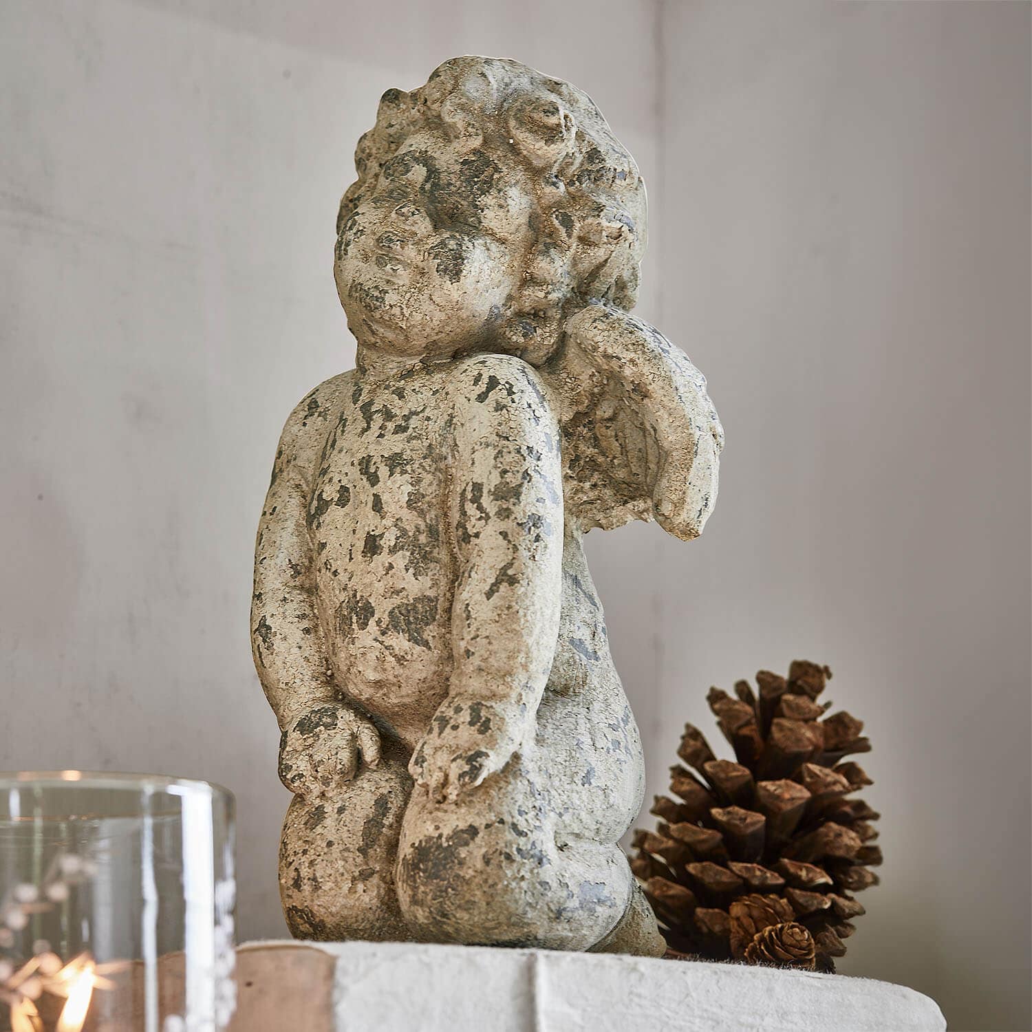 Engelsfigur aus gealtertem Stein in Beige, Wohnaccessoire mit natürlicher Kieferzapfen-Dekoration
