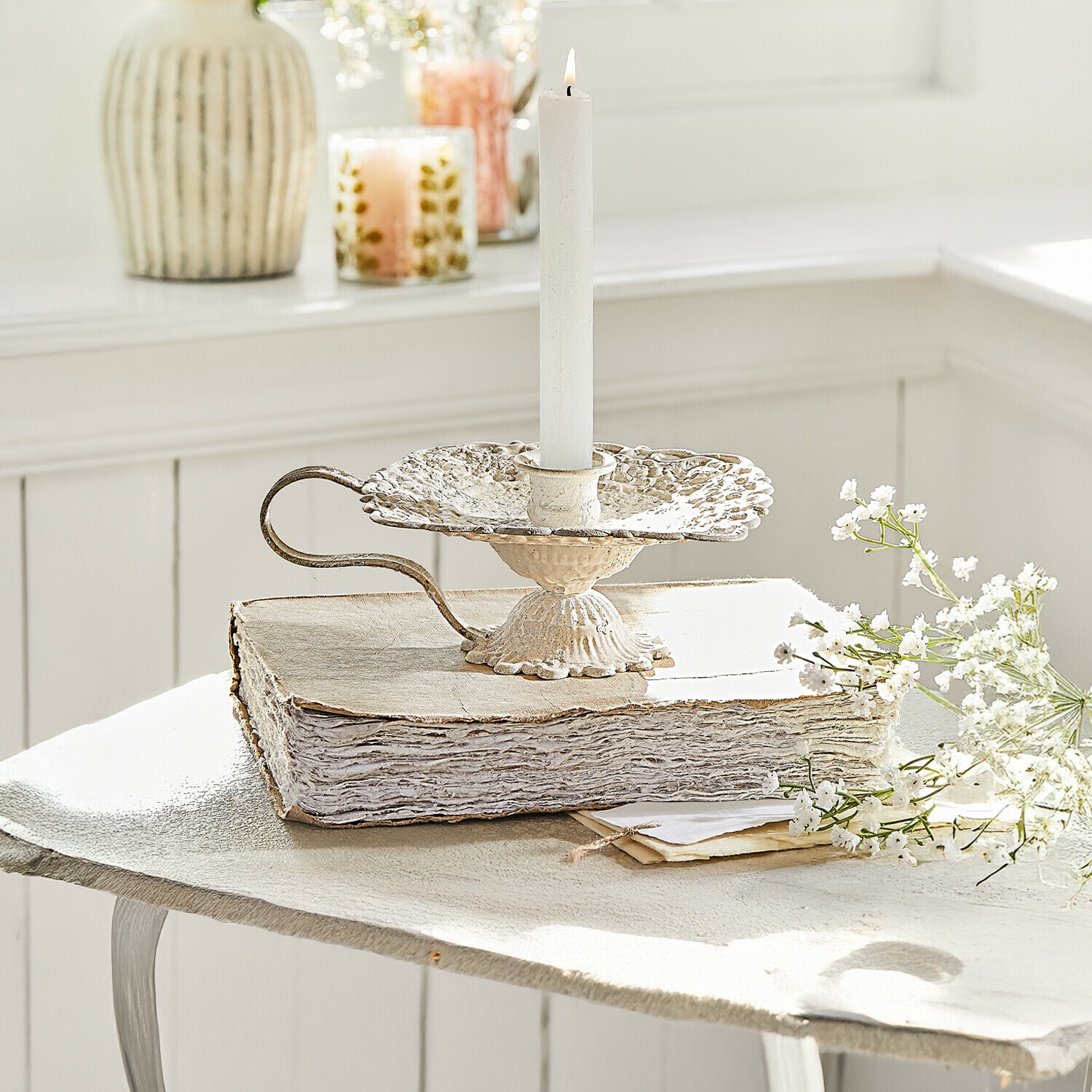 Kerzenhalter Wilexor Vintage Metall-Kerzenhalter in Creme mit weißer Kerze, dekorativ auf altem Buch mit Blumen arrangiert