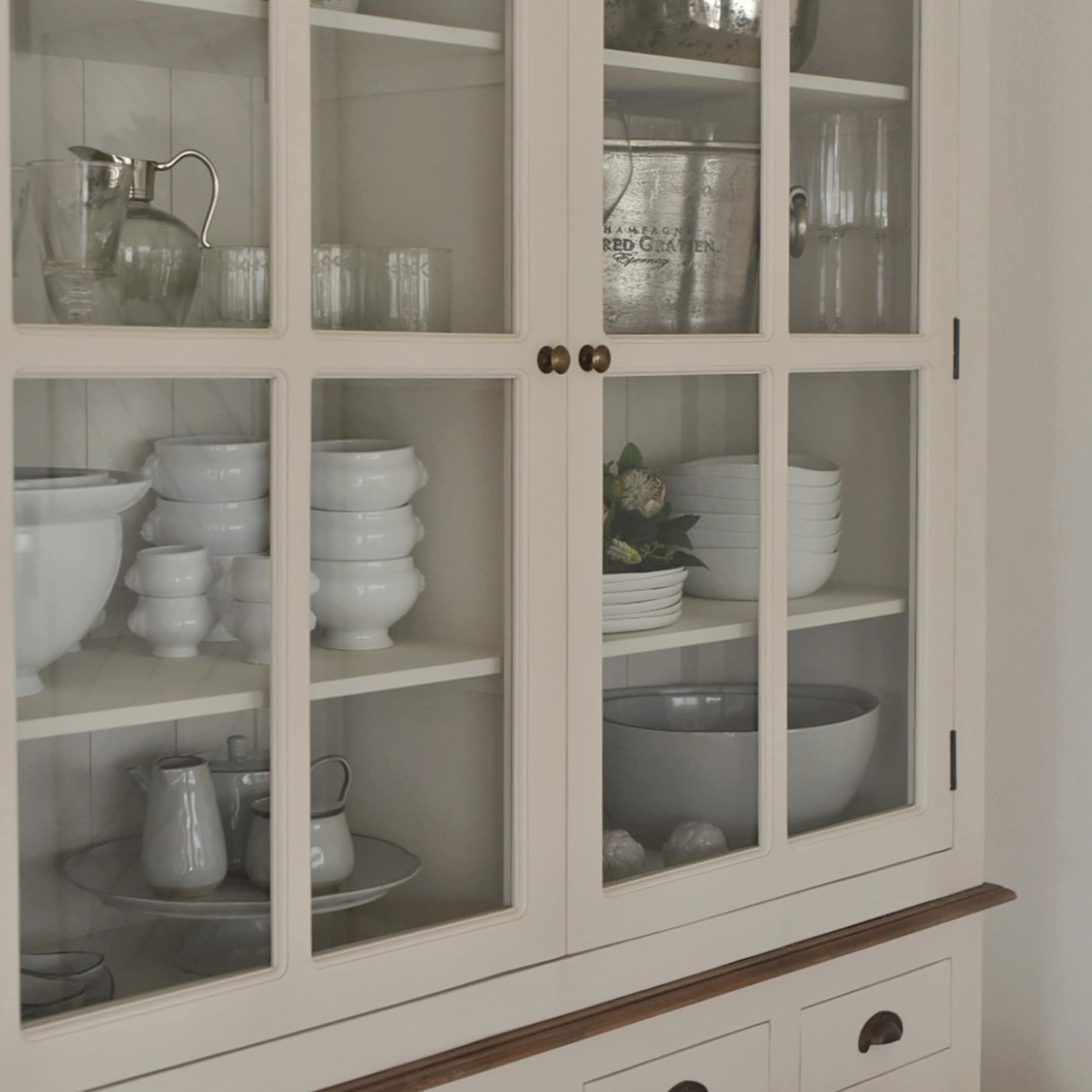 Weißer Holzschrank mit Glastüren, weißem Porzellan und Gläsern im Inneren