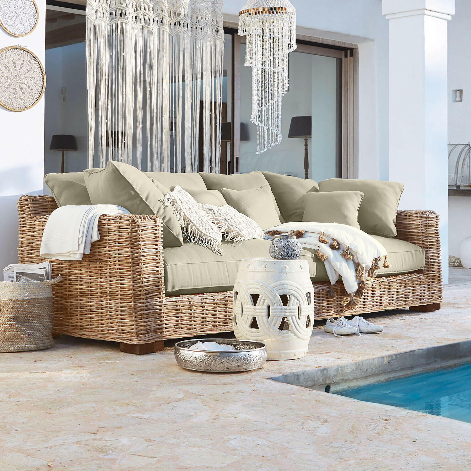 Sofa Rimini Rattansofa mit beigen Kissen und Boho-Dekorationen neben dem Pool im Außenbereich